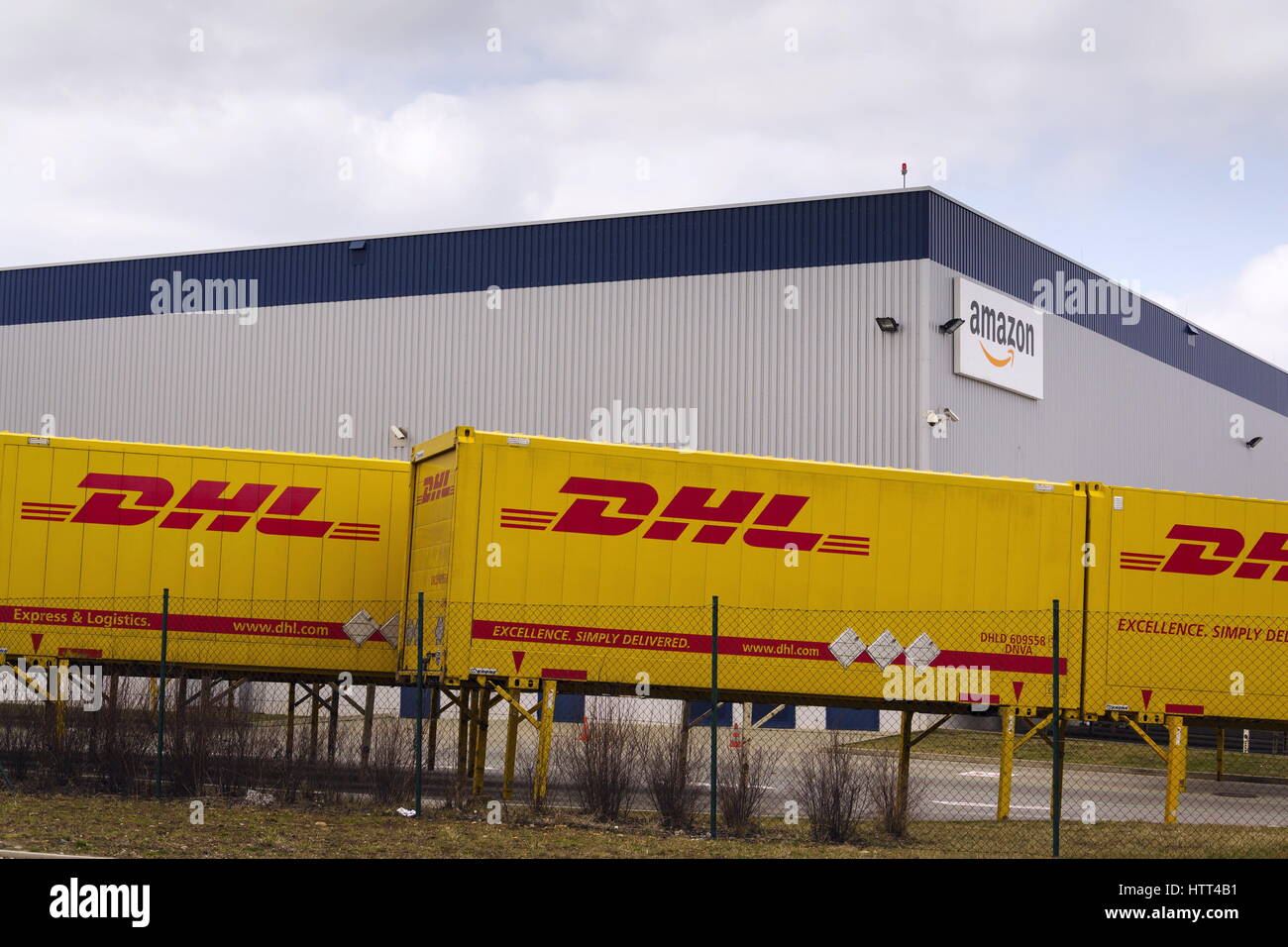 DOBROVIZ, CZECH REPUBLIC - MARCH 12: DHL shipping containers in front of Amazon logistics building on March 12, 2017 in Dobroviz, Czech republic. Stock Photo