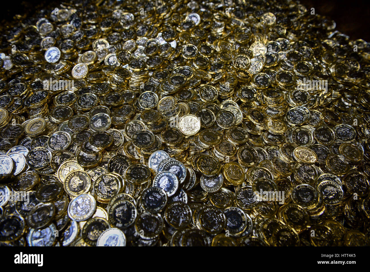 Editorial Use only &ETH; NO COMMERCIAL USE New 12-sided one pound coins fall into a metal crate as they are minted at the Royal Mint in Llantrisant, Wales. Stock Photo