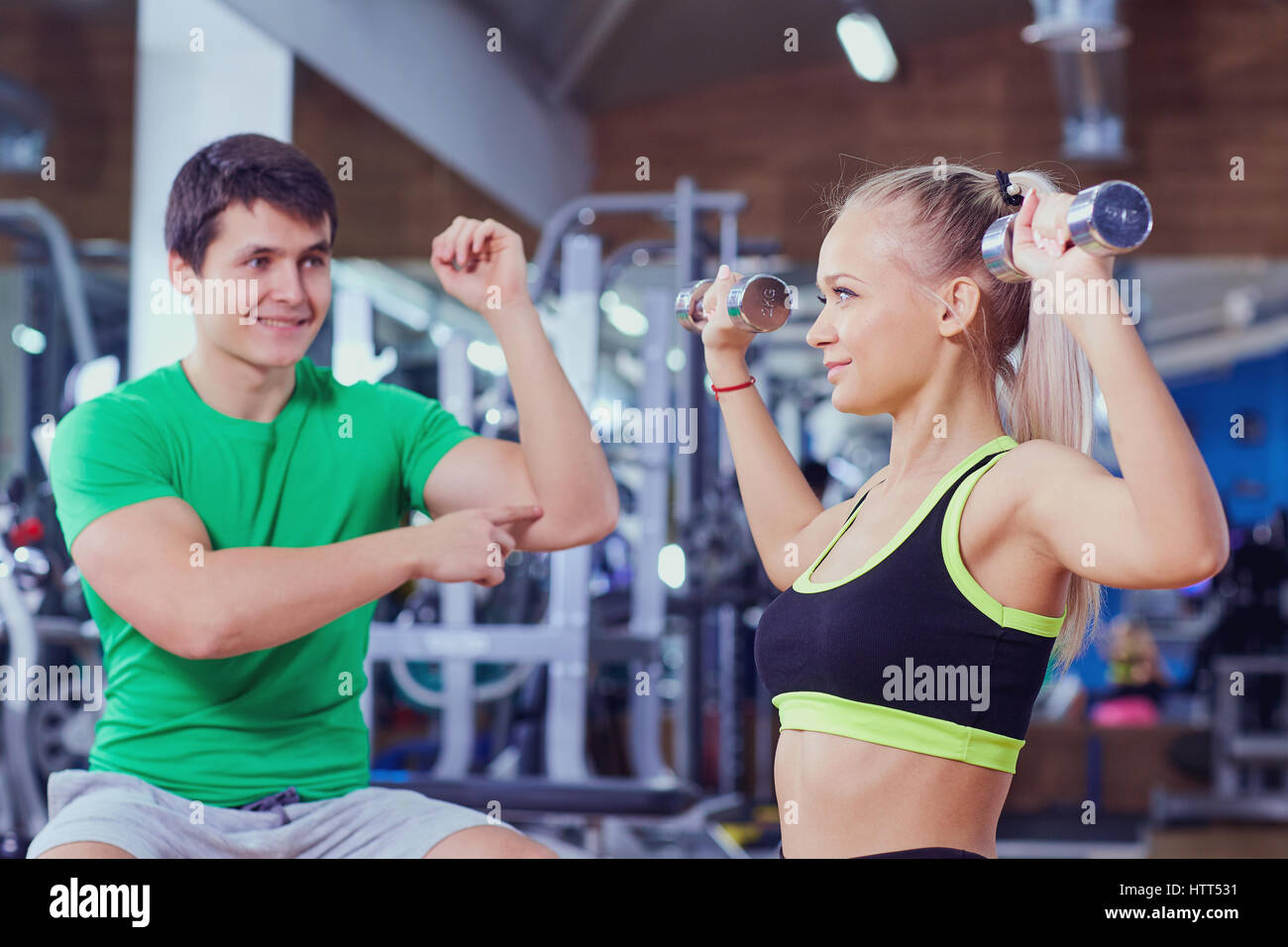 Personal trainer and girl with dumbbells doing exercises in the gym ...