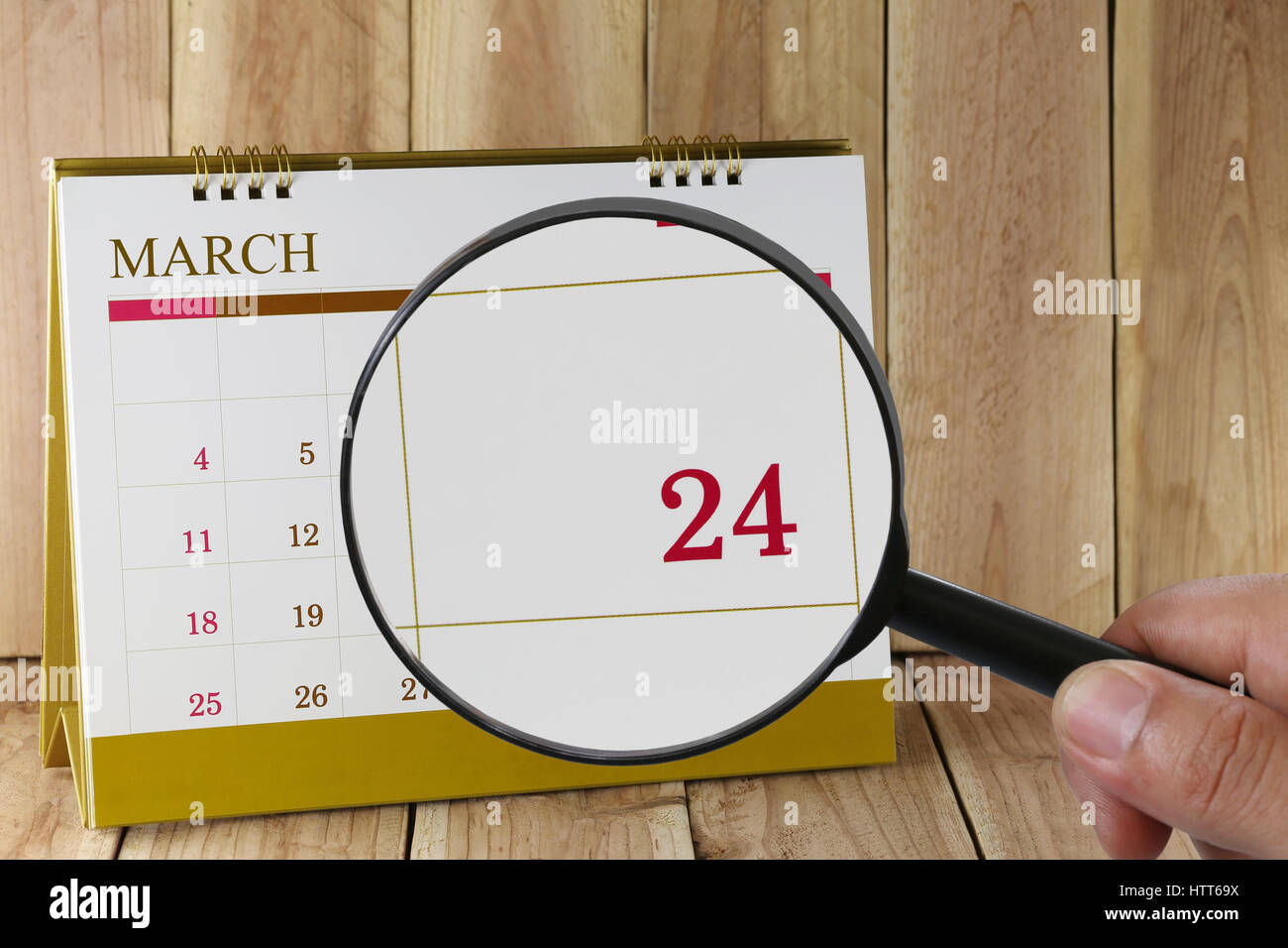 Magnifying glass in hand on calendar you can look Twenty-four day of month,Focus number Twenty-four in March,Concept in business and meetings. Stock Photo