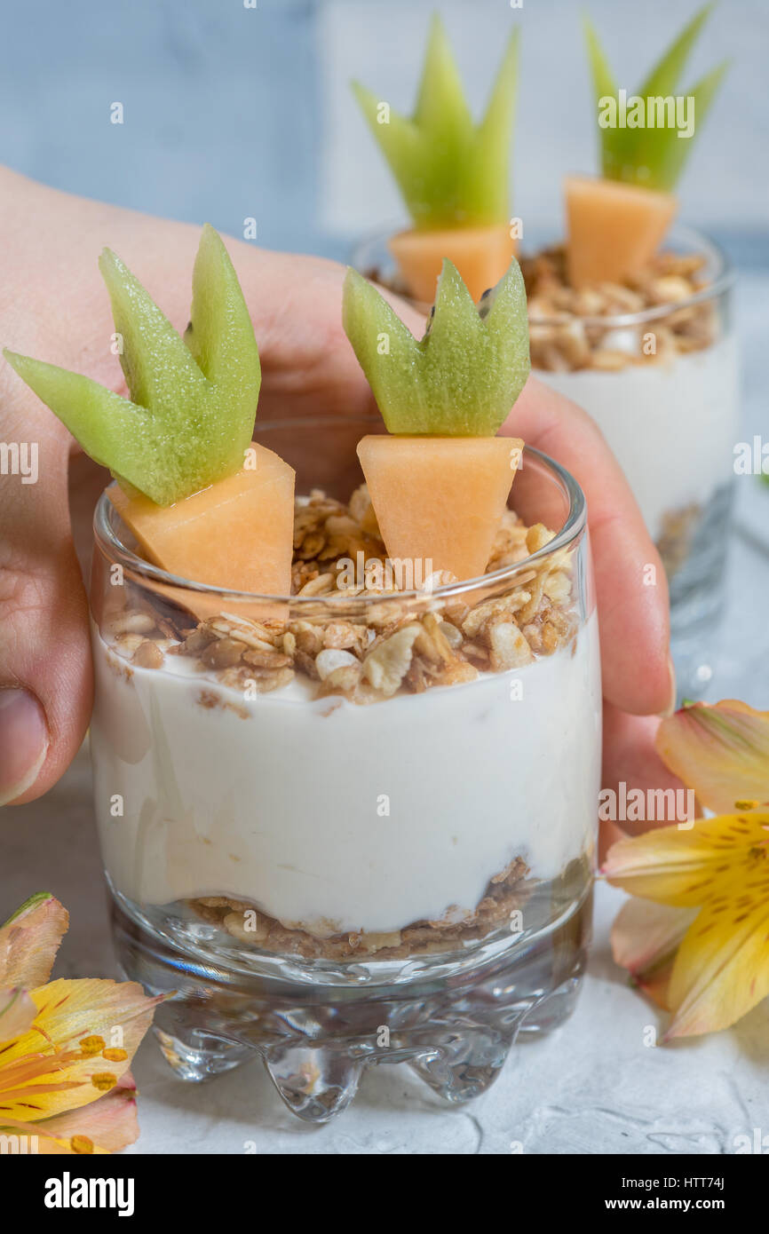 Fresh Fruit Parfait with yogurt and granola, carrot shape melon and kiwi for Easter breakfast Stock Photo