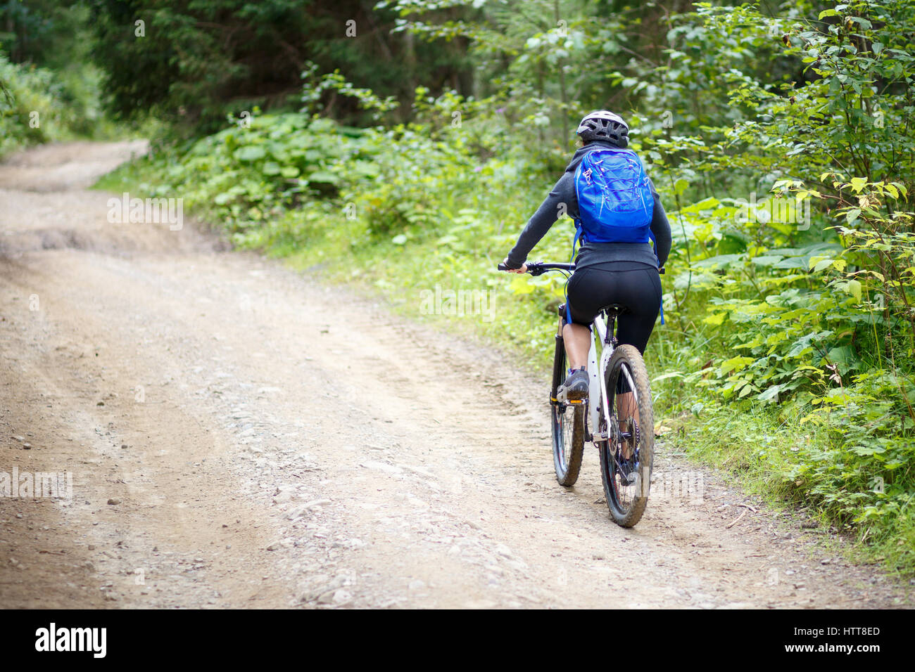 Young woman with backpack riding bicycle on mountain road in the forest Stock Photo Alamy
