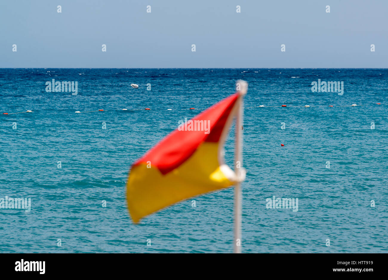 Red and yellow flag on the beach on the background of the sea Stock