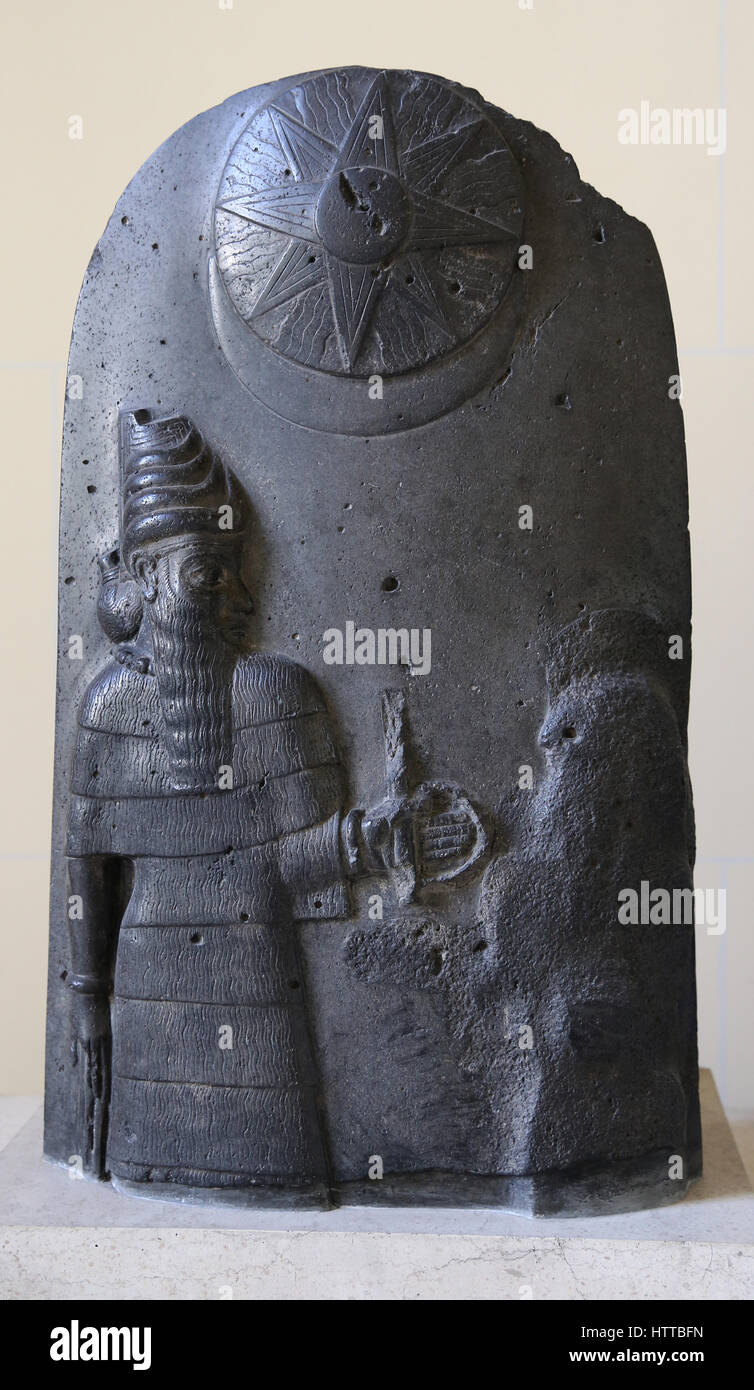 Mesopotamian stele, usurped by the Elamites. A god with orant (damaged). Sun and moongod symbols. Susa, Iran, Basalt. 12th BCE. Louvre Museum. Stock Photo