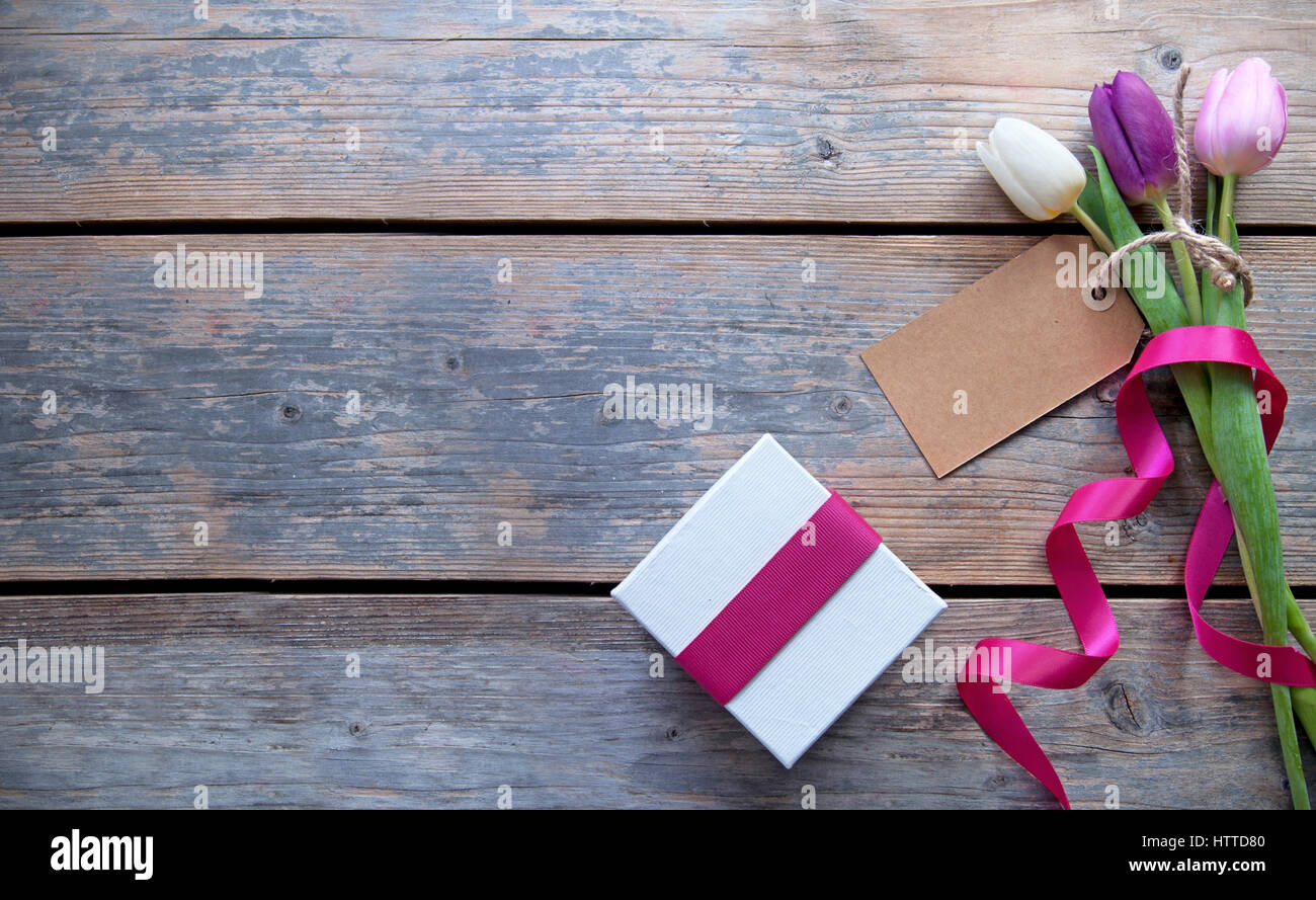 Flowers with blank gift label over a wooden background Stock Photo