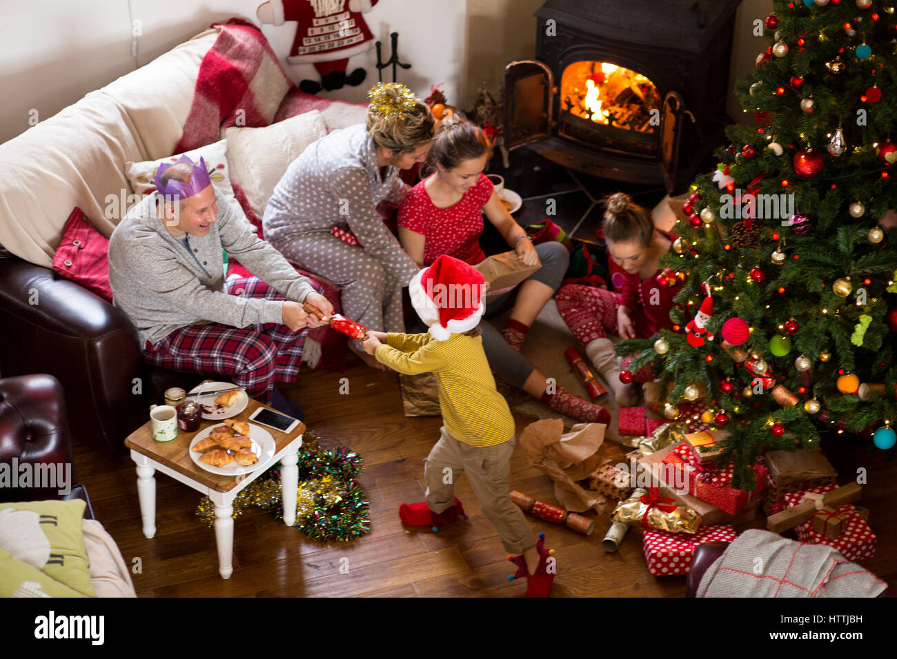 Family at Christmas. They are opening presents and pulling crackers. Stock Photo