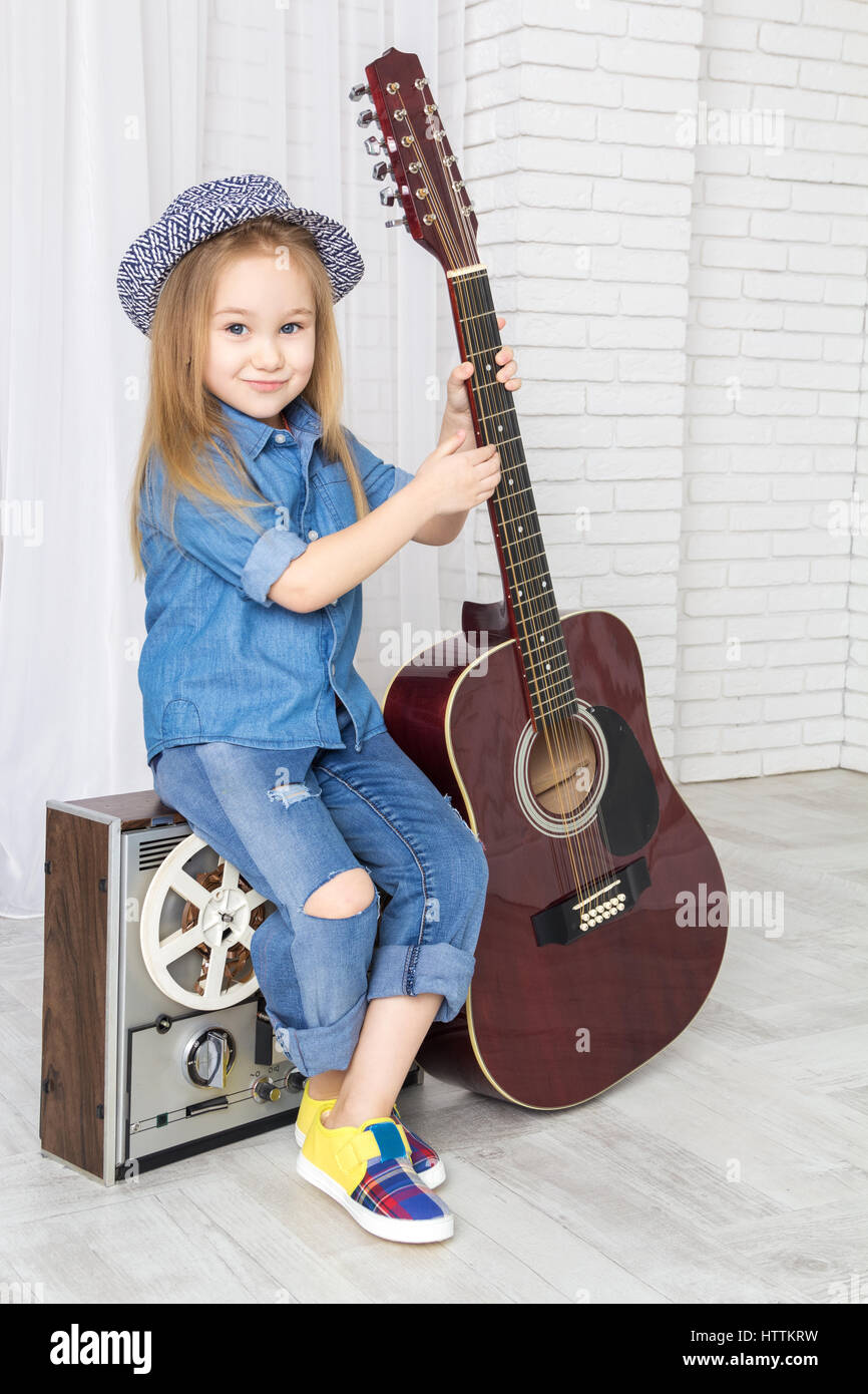 little girl with a guitar sitting on retro tape Stock Photo
