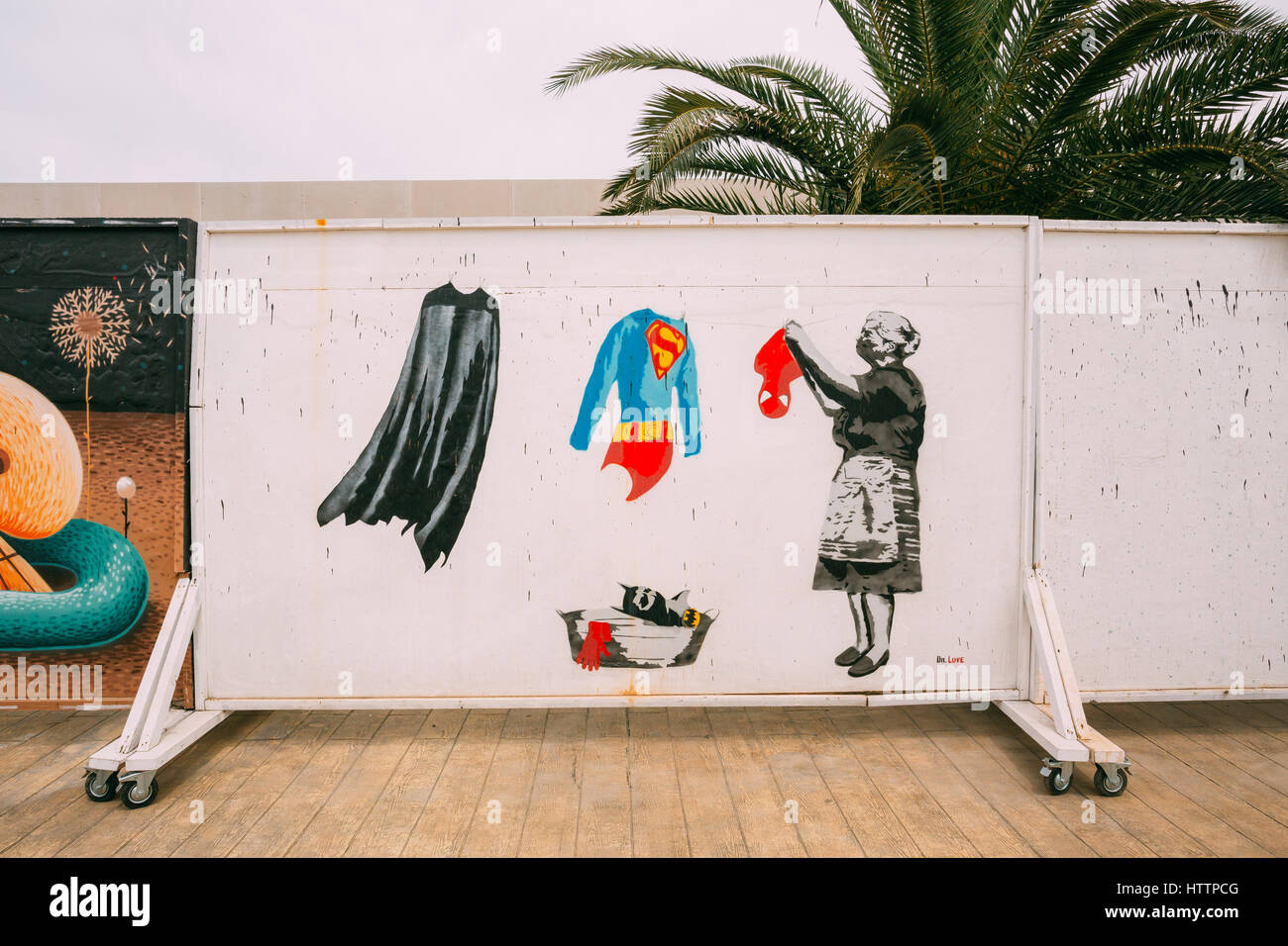 Batumi, Adjara, Georgia. Street graffiti by Dr. Love with Grandmother hanging clothes suits of superheroes - Batman's raincoat, Superman's clothes and Stock Photo