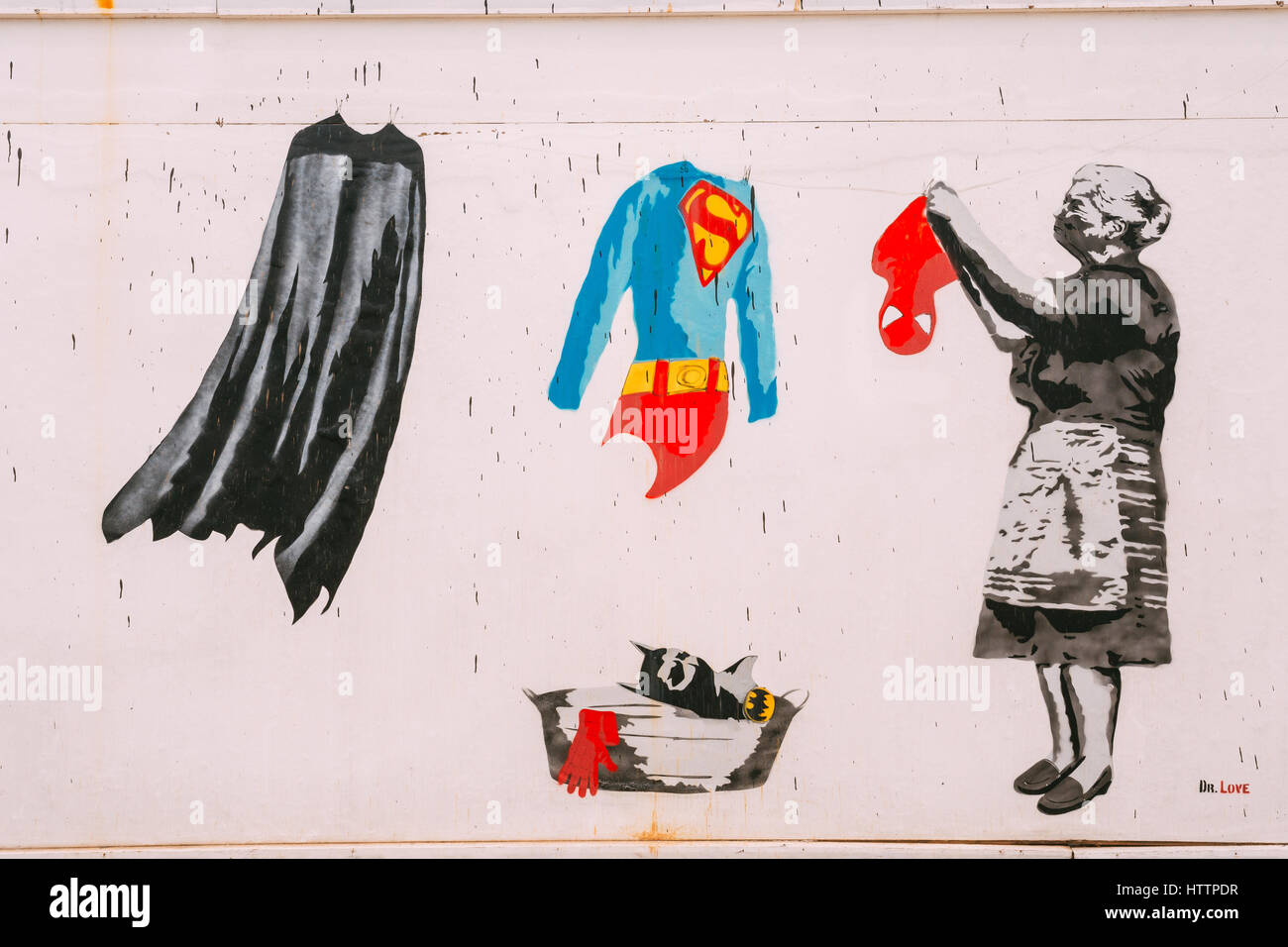 Batumi, Adjara, Georgia. Street graffiti by Dr. Love with Grandmother hanging clothes suits of superheroes - Batman's raincoat, Superman's clothes and Stock Photo