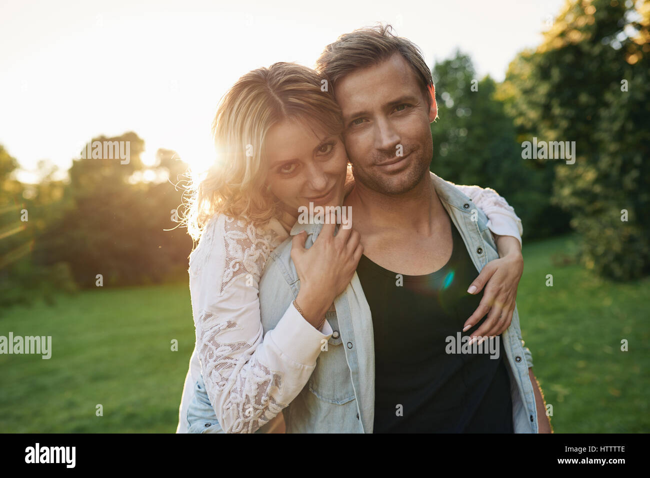 Portrait of a smiling young woman hugging her husband from behind while ...