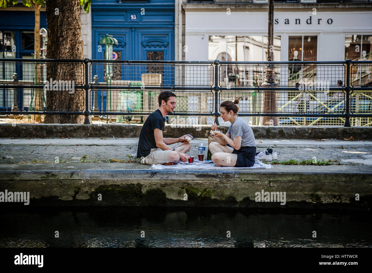 Couple havin lunch at the canal Saint-Martin shore, Paris, France Stock Photo