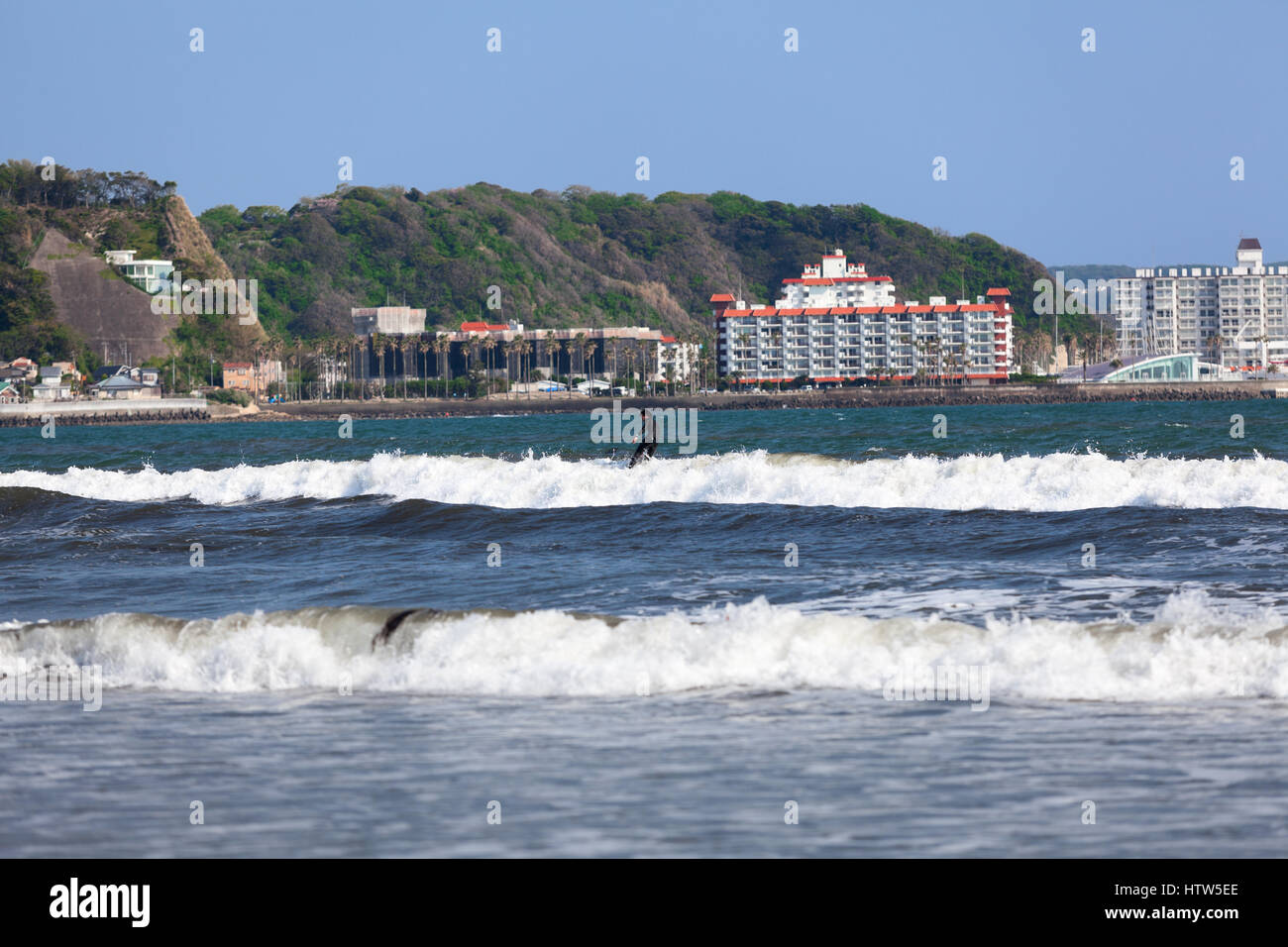KAMAKURA, JAPAN - CIRCA APR, 2013: Japanese surfer stands on the top of the wave. The Yuigahama beach. The Sagami Bay is famous for surfing. Coast of  Stock Photo