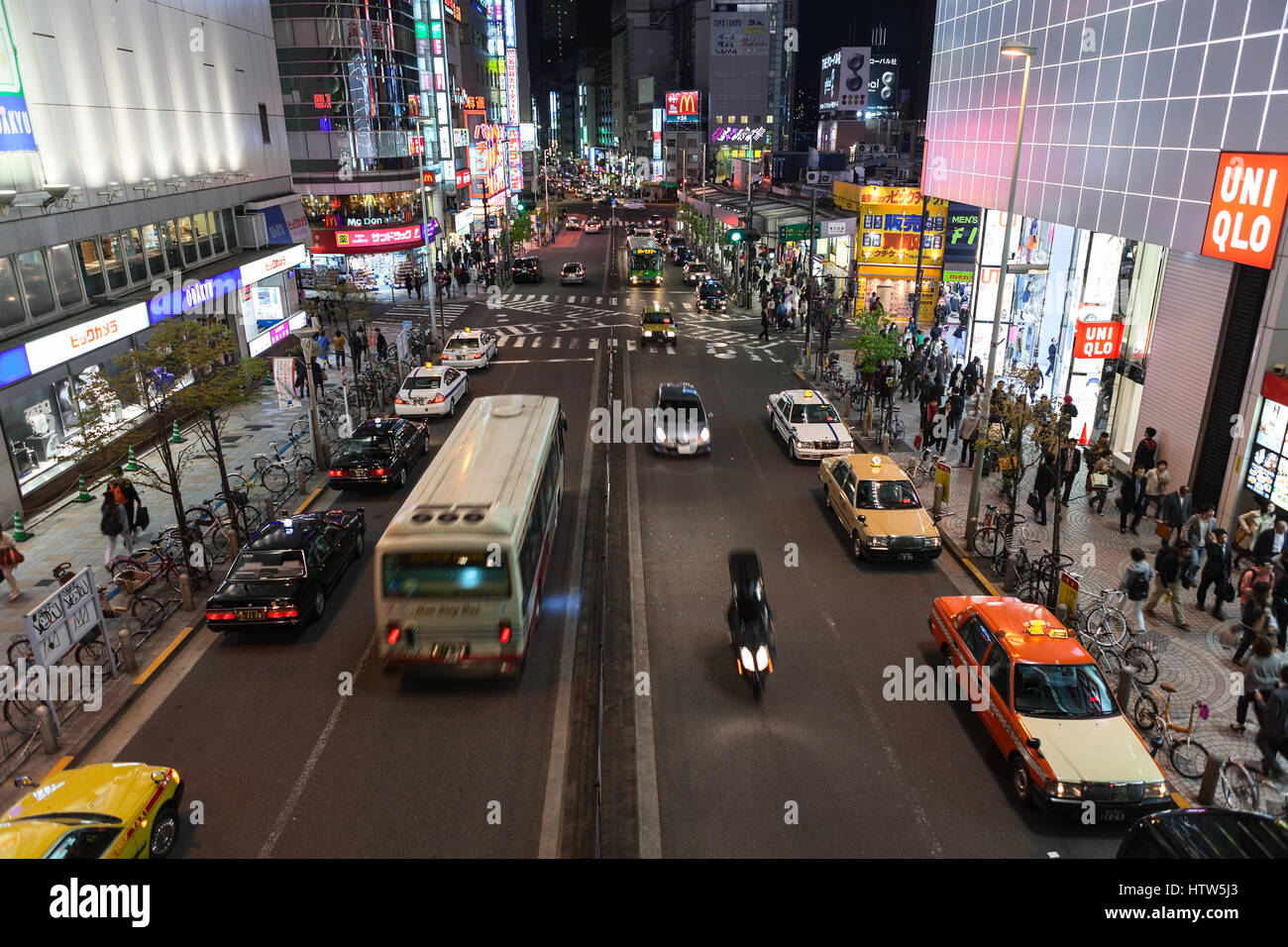 TOKYO, JAPAN - CIRCA APR, 2013: Crossroad with vehicles is in downtown. Illuminated advertising banners are on building facades. Nightlife is on the s Stock Photo