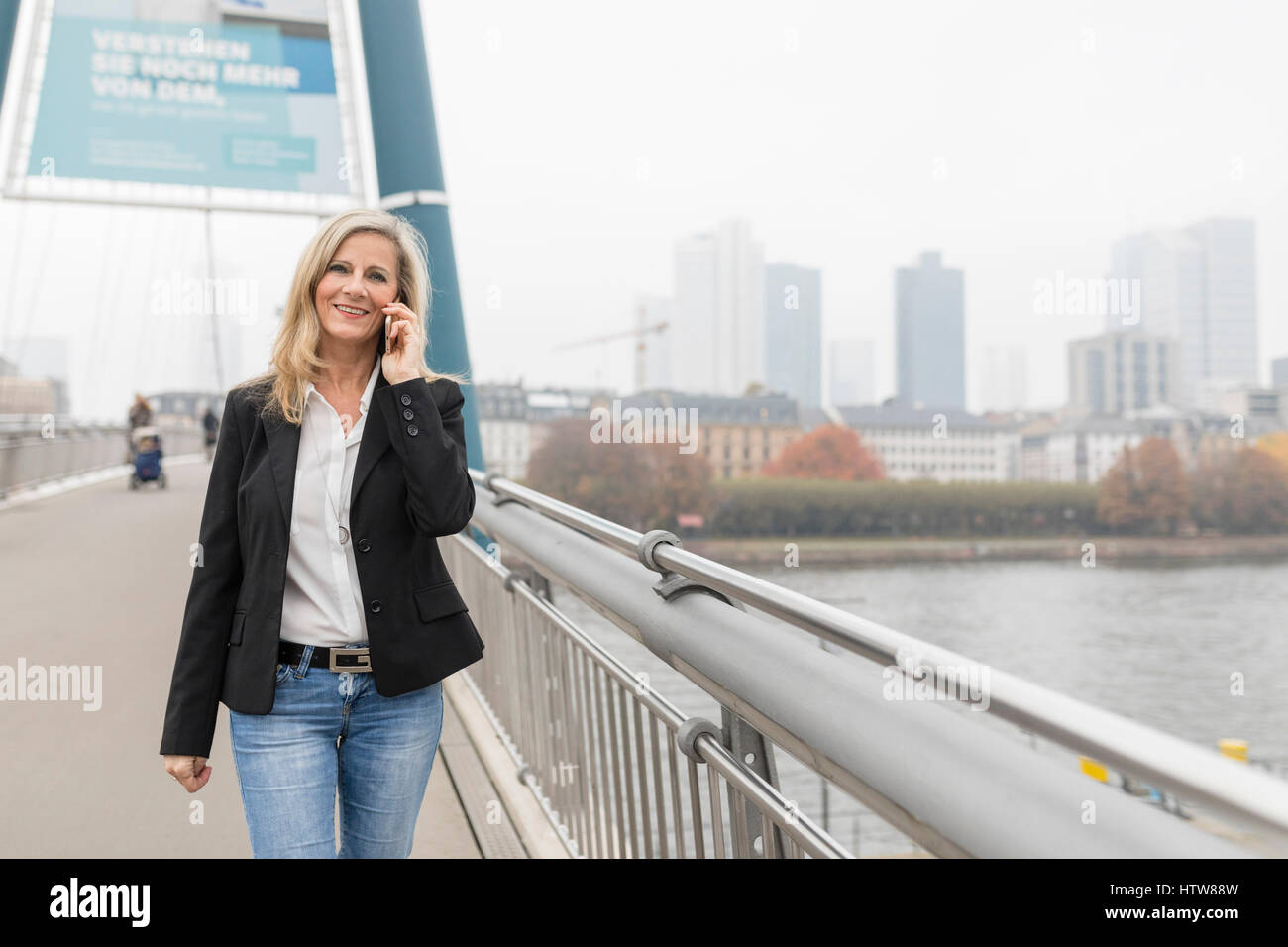 Businesswoman phoning on a bridge Stock Photo