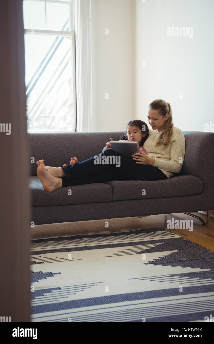 Mother and daughter using digital tablet in living room Stock Photo