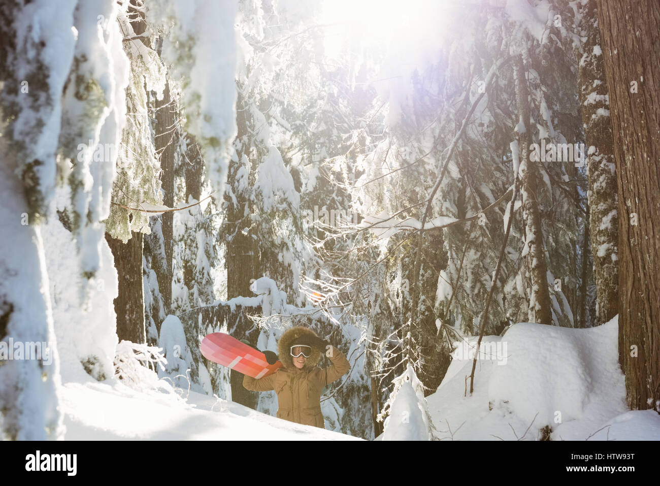 Woman with snowboard walking on snowy mountain Stock Photo