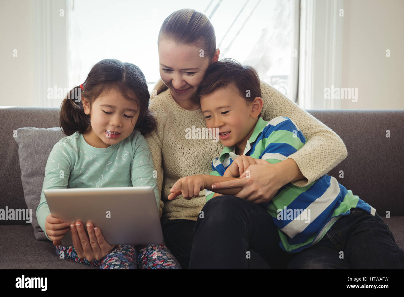 Mother and kids using digital tablet in living room Stock Photo