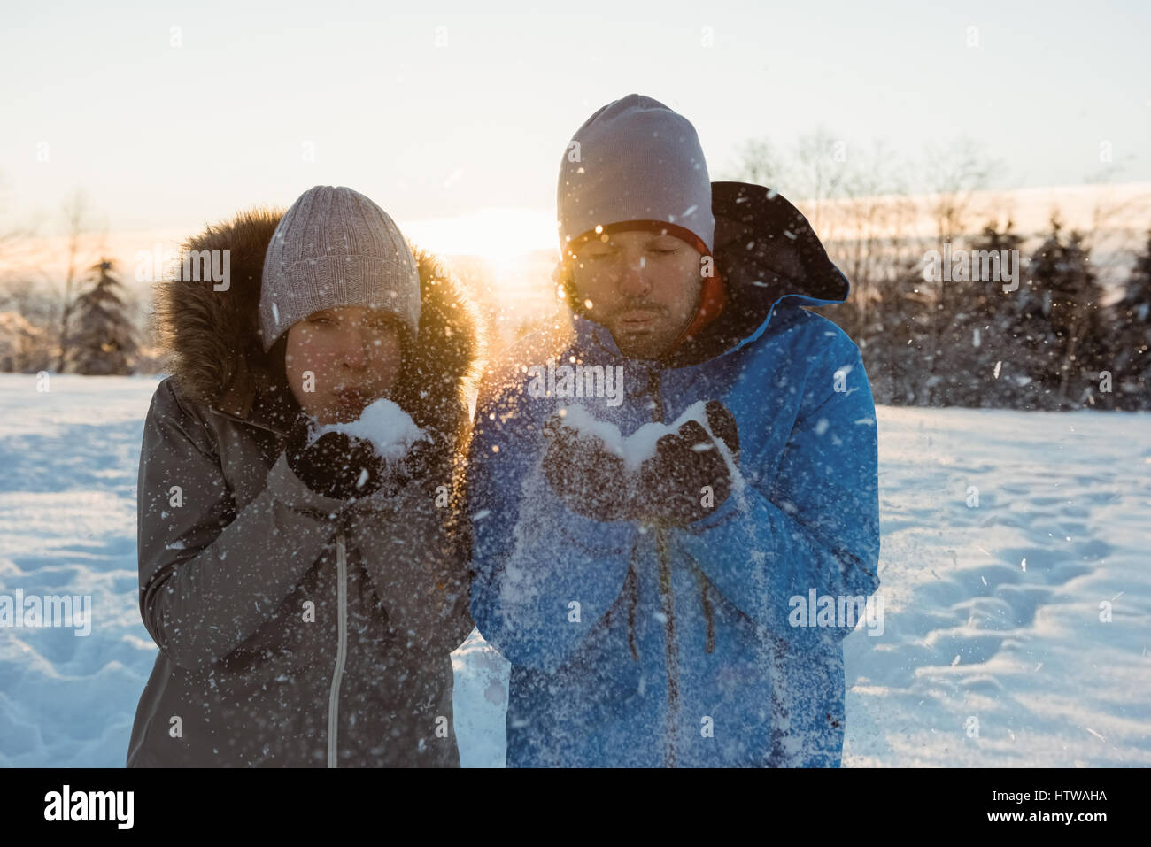 Couple blowing snow in sunny winter day Stock Photo