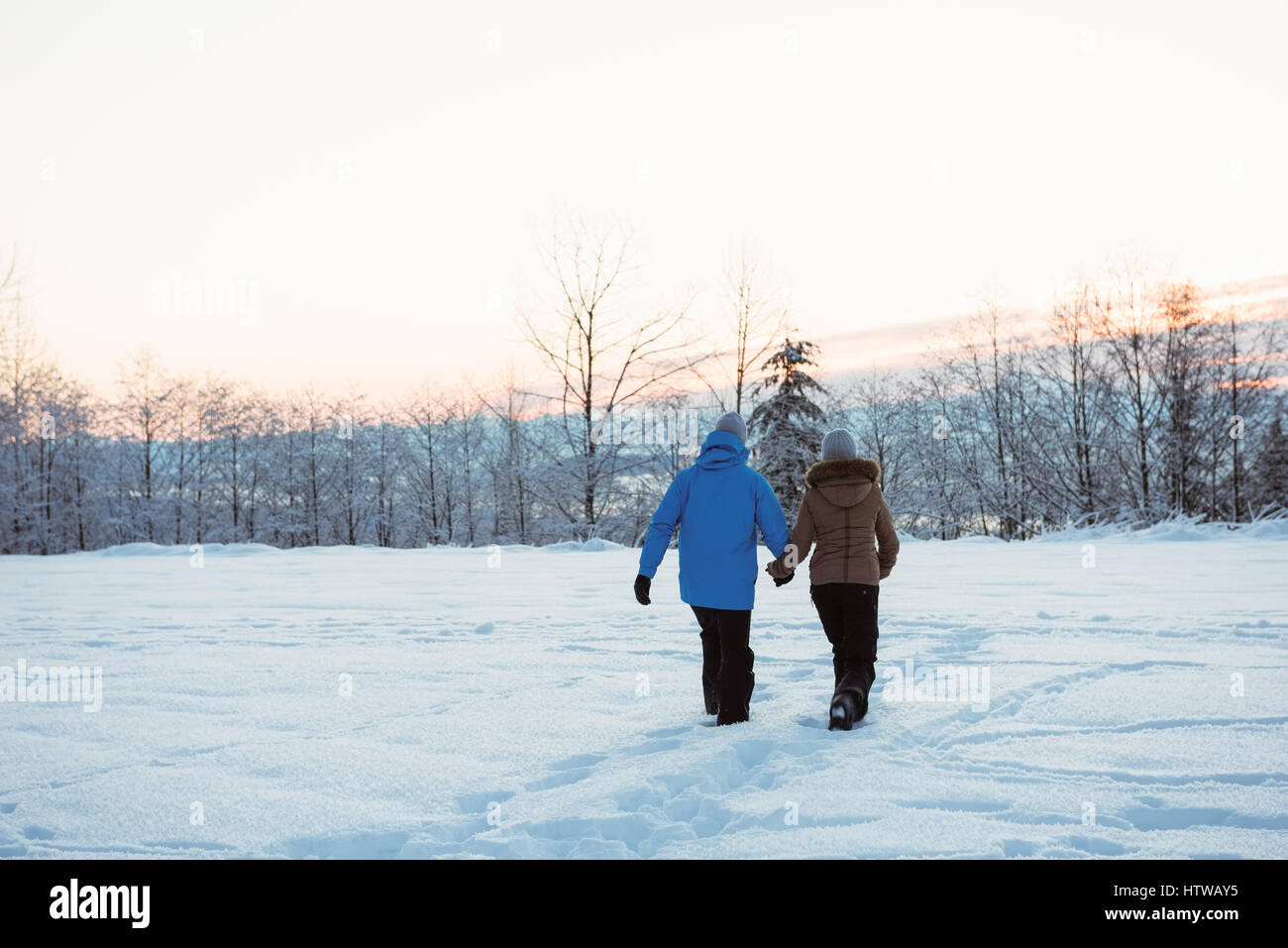 Couple walking on snow covered mountain Stock Photo