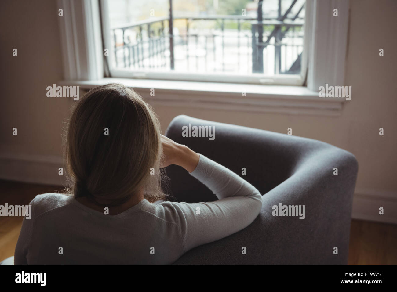 Rear view of woman sitting on sofa in living room Stock Photo