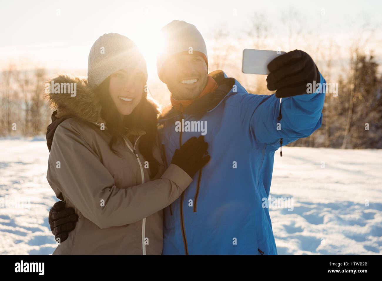 Happy couple taking a selfie on snowy landscape Stock Photo - Alamy