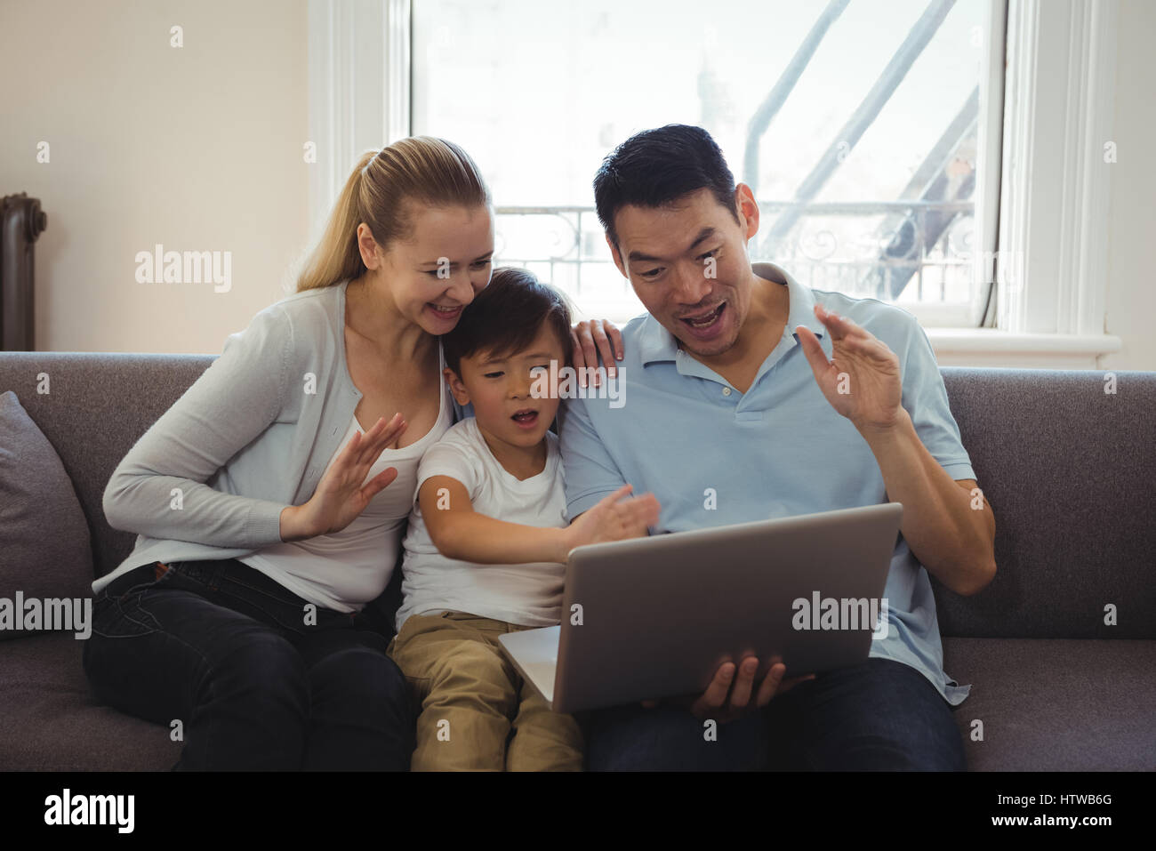 Family having video chat on laptop in living room Stock Photo