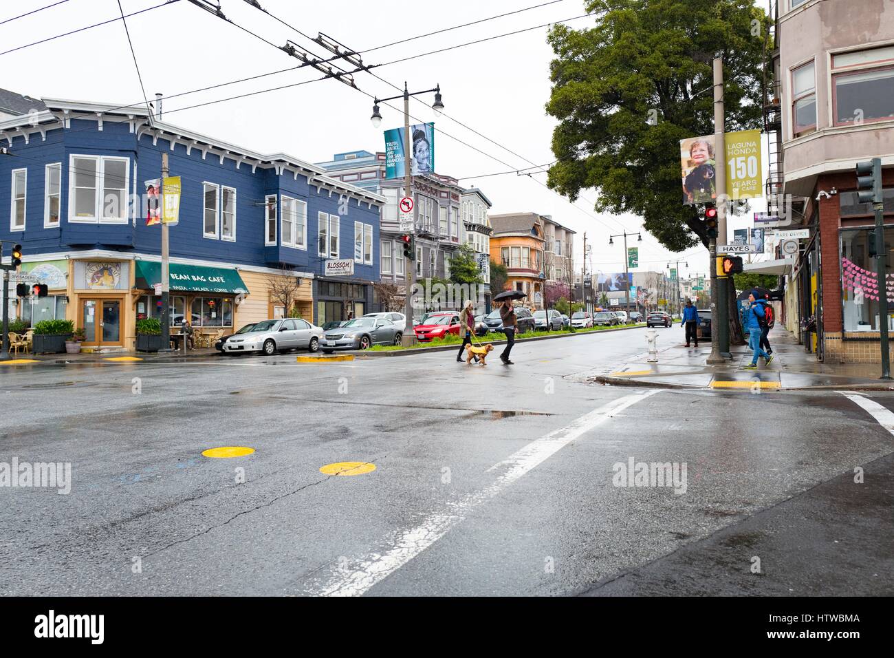 On a rainy day in the North of Panhandle (NoPA) neighborhood of San Francisco, California, people cross at the intersection of Divisadero Street and Hayes Street, February 19, 2017. Stock Photo