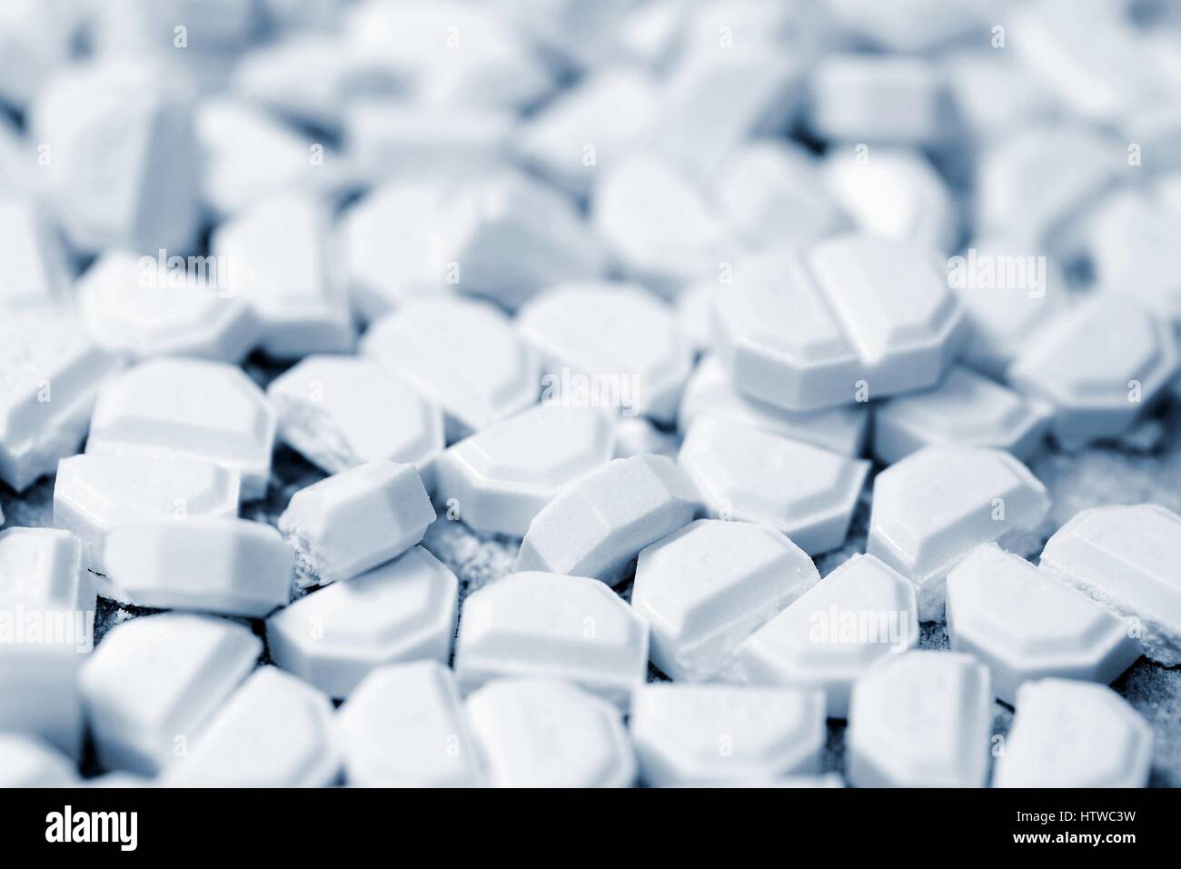 Macro of white tablets cut into small pieces. Blue color toned. Stock Photo