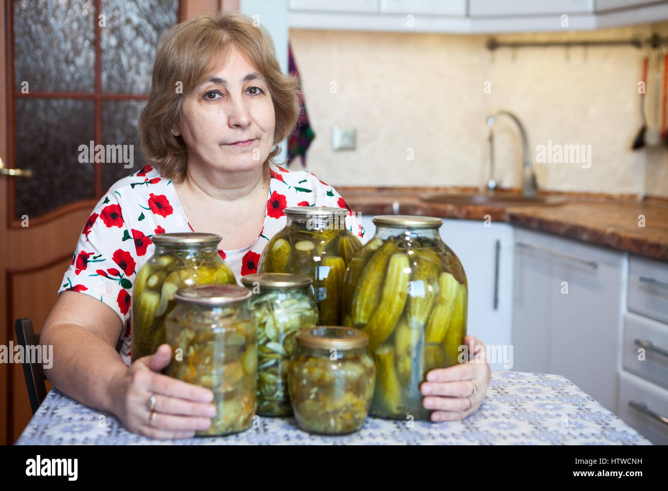 russian mature homemade Caucasian Russian middle-aged woman sits at a table in kitchen with glass  jars full of pickles Stock Photo - Alamy