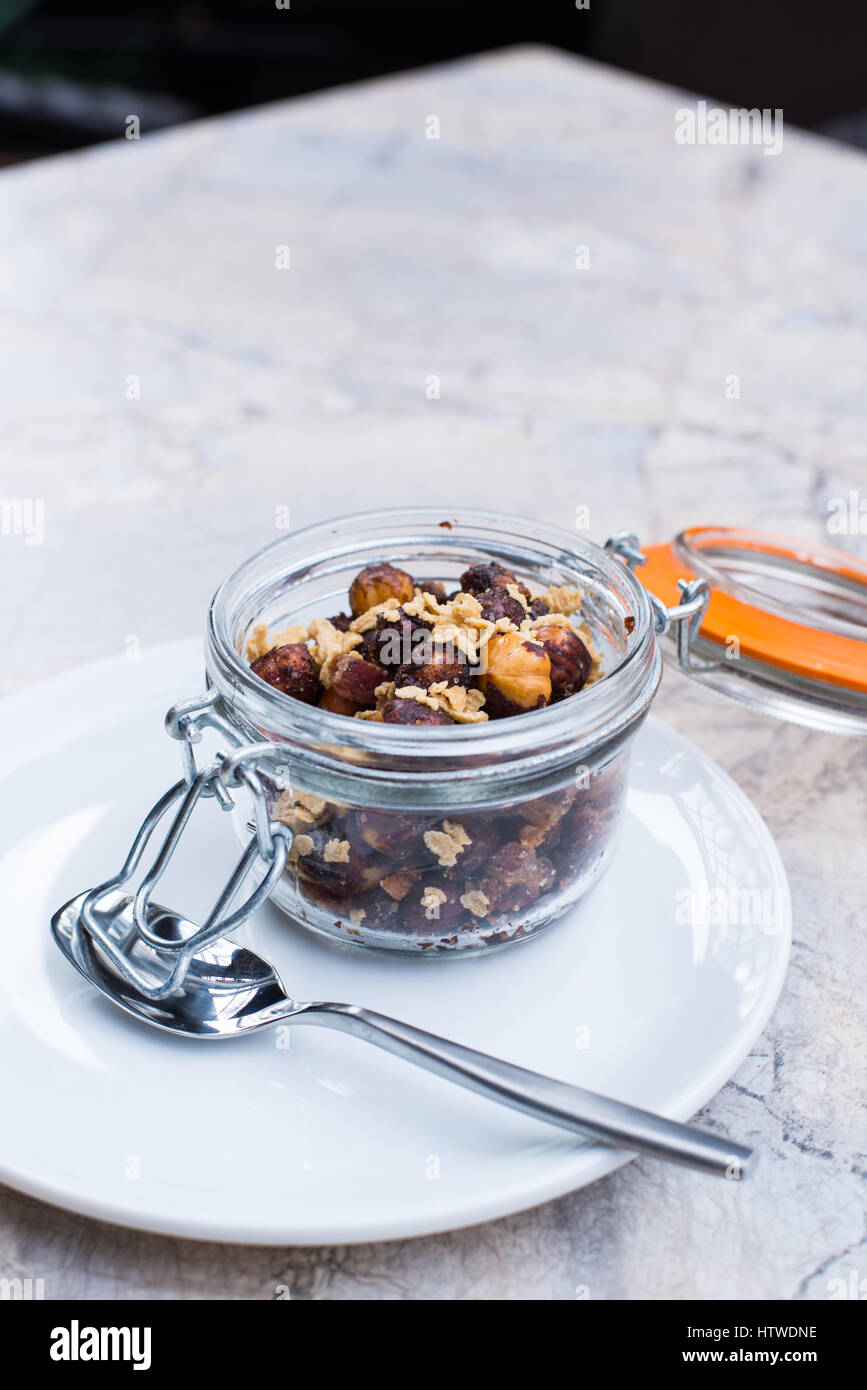 3/4 view of beer nuts in a clasp-top jar on a small white plate with a spoon Stock Photo