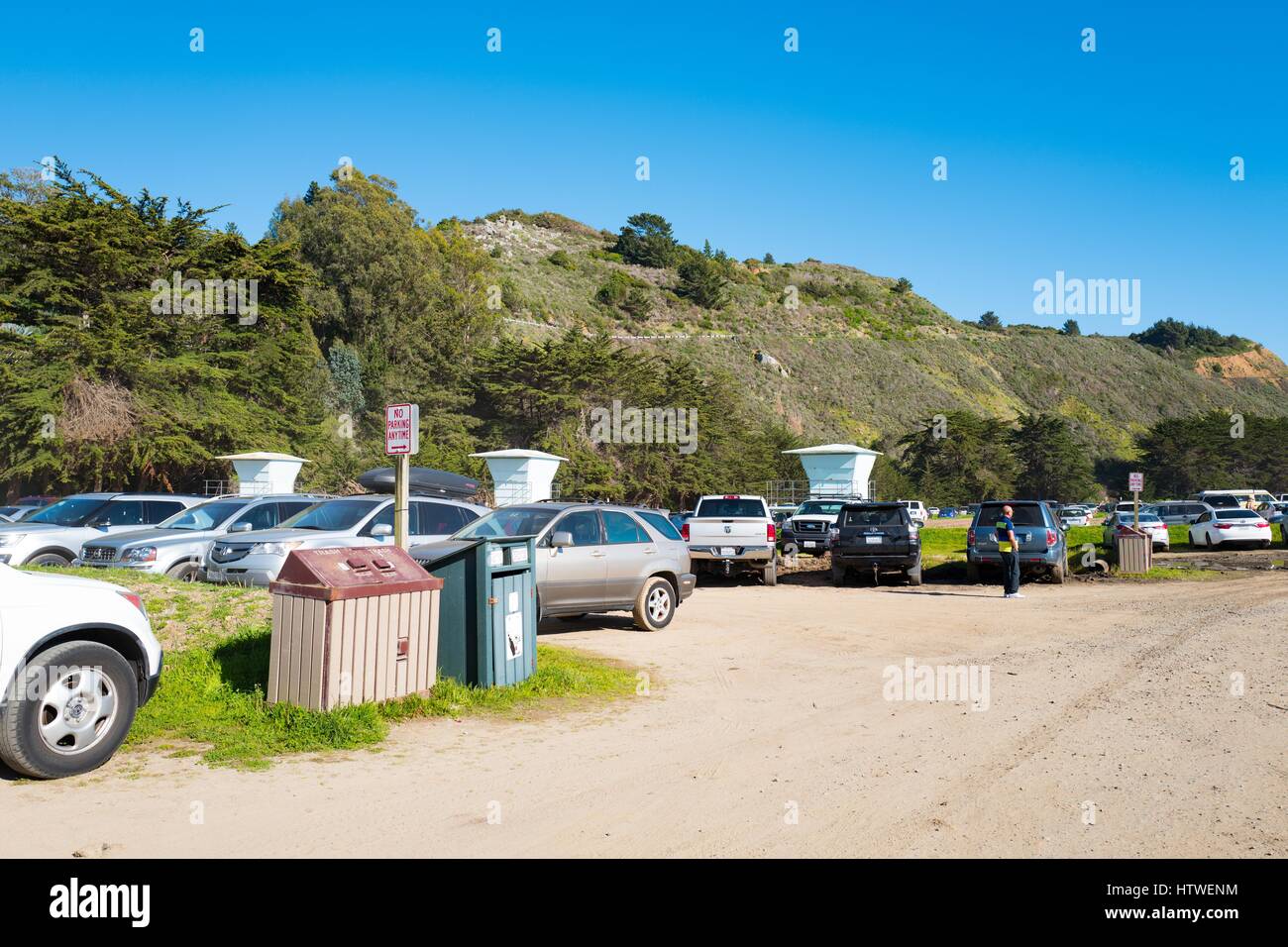 Cars are parked in a rugged, unpaved parking lot in the remote Marin