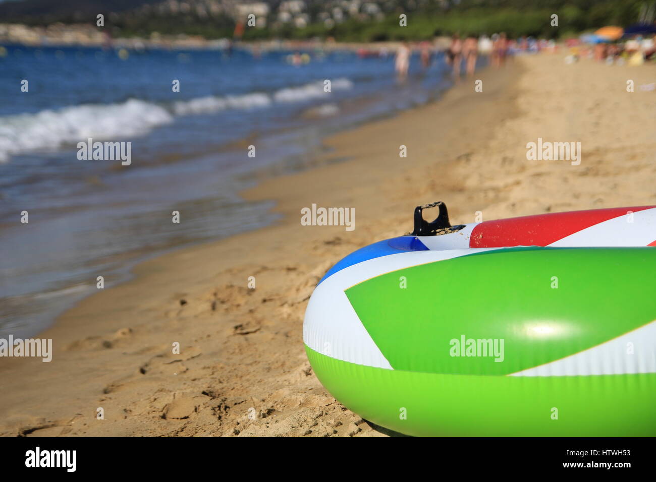 Colorful inflatable ring on a beautiful sandy beach in the summer sunshine Stock Photo