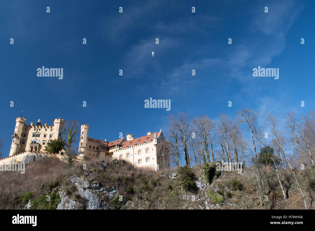 Castle on hill with paraglider gliding in the Sky above - Hohenschwangau Caslte Stock Photo