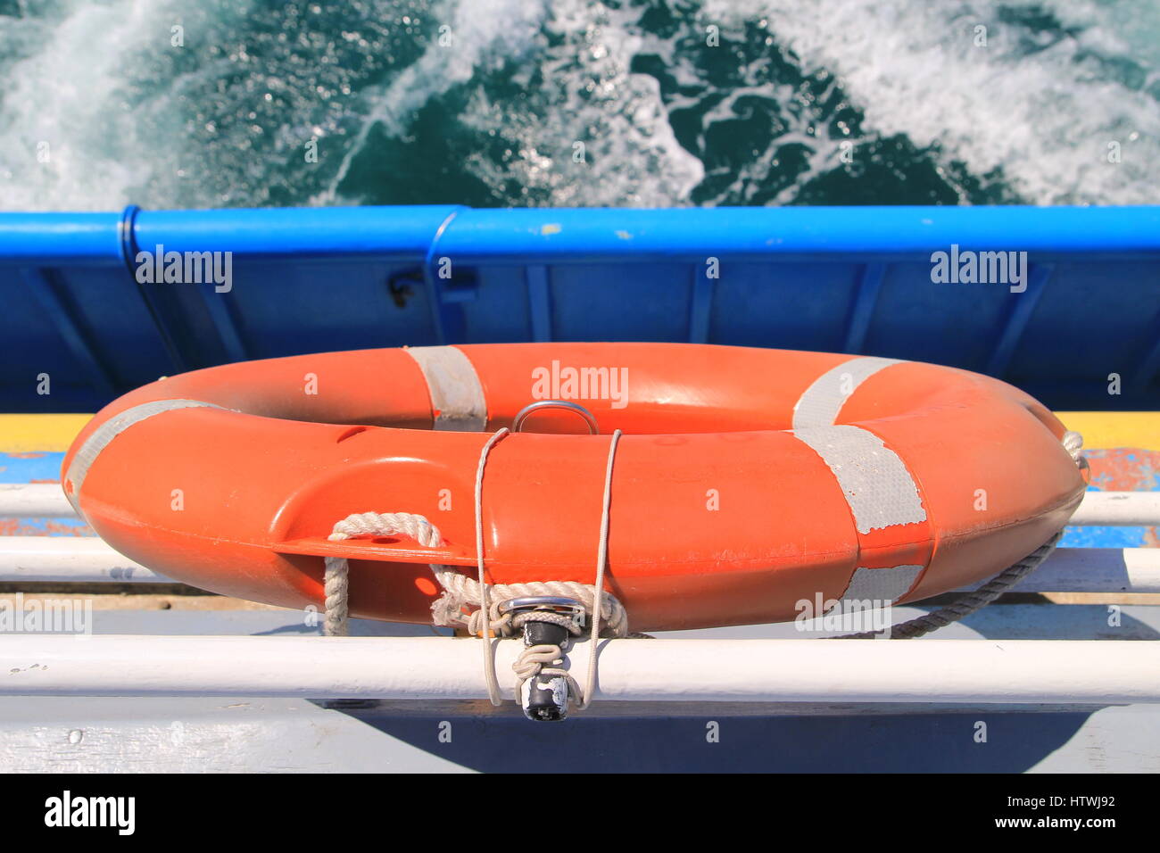Lifebelt on rear of a boat, with white foam of the wake in background