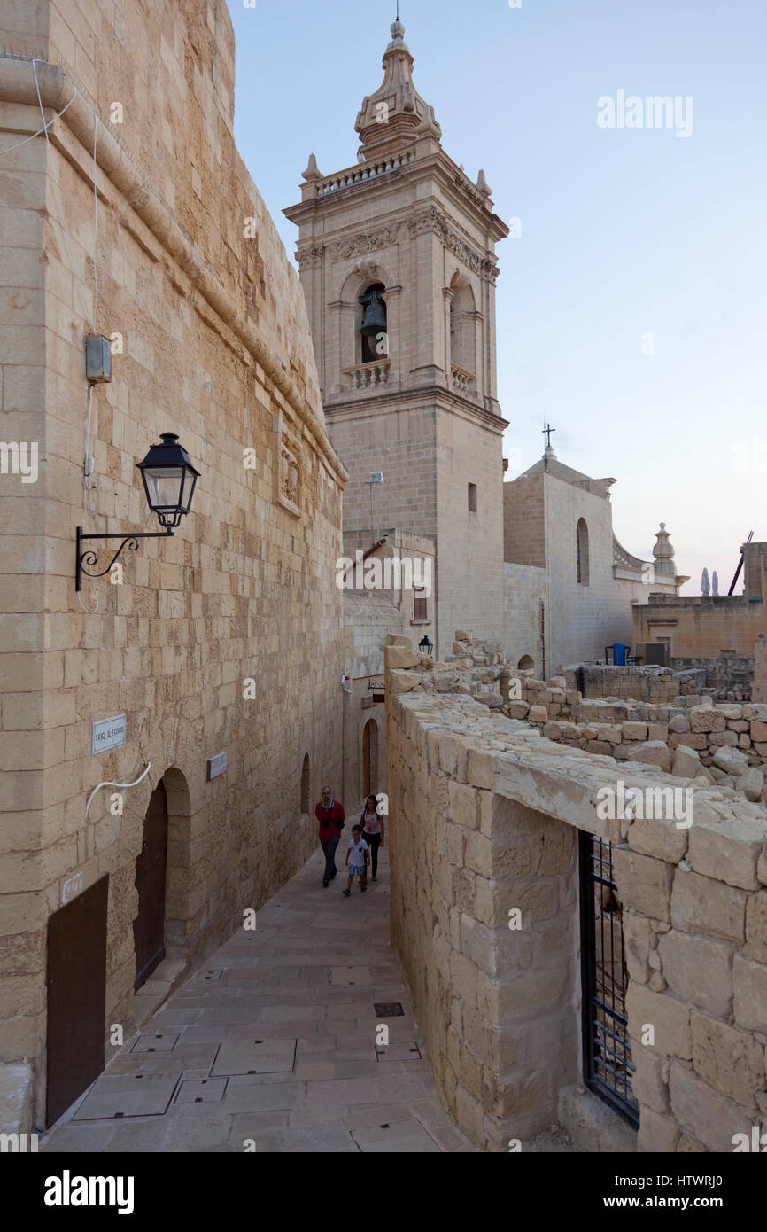 A family of tourists explore the alleys of the Citadel near the Cavalier and church in the Citadel in Gozo. Stock Photo