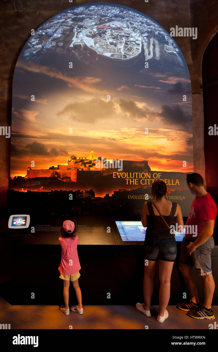 Vistors explore video screens with info and large pictures at the visitors' centre of the Citadel in Gozo. Stock Photo