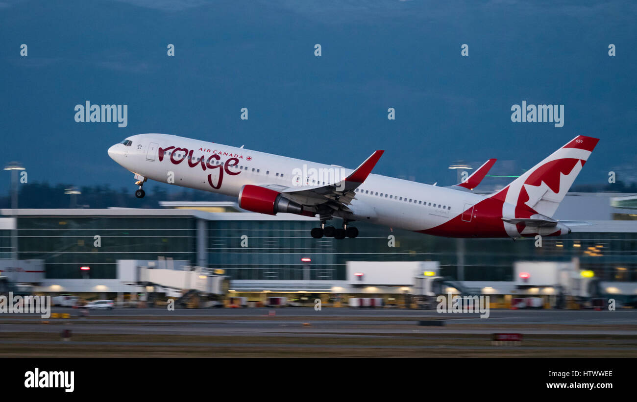 Air Canada Rouge plane airplane Boeing 767 (767-300ER) wide-body jet airliner take taking off at dusk twilight Vancouver International Airport Stock Photo