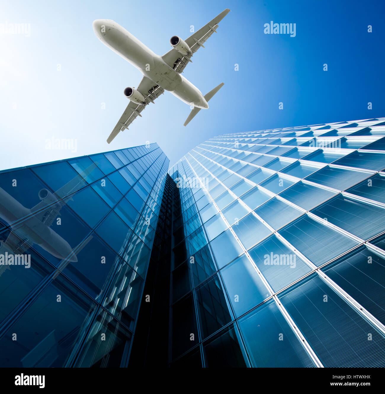 Skyscrapers with a flying airplane against blue sky Stock Photo - Alamy