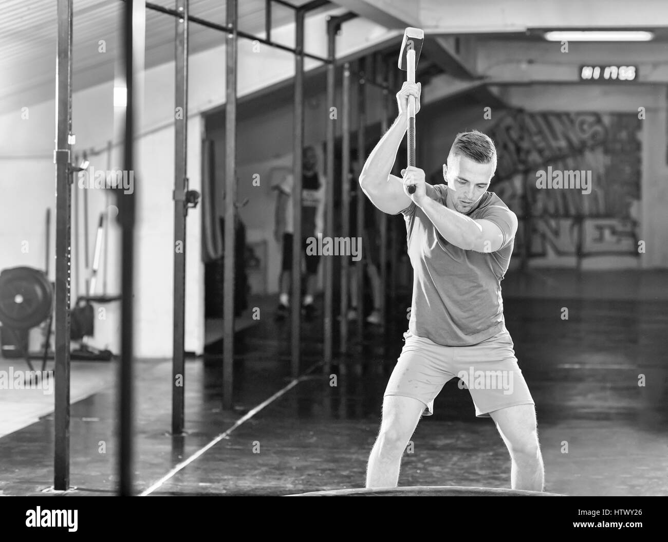 Sledgehammer Tire Hits young muscular man workout at gym with hammer