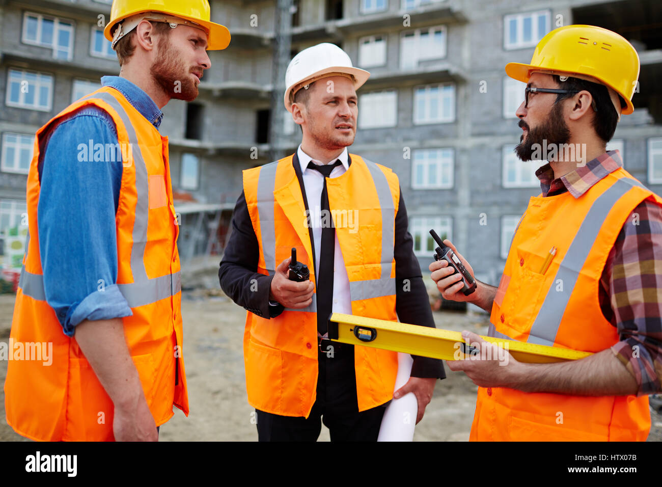 Young builders with walkie-talkies interacting at construction-site Stock Photo