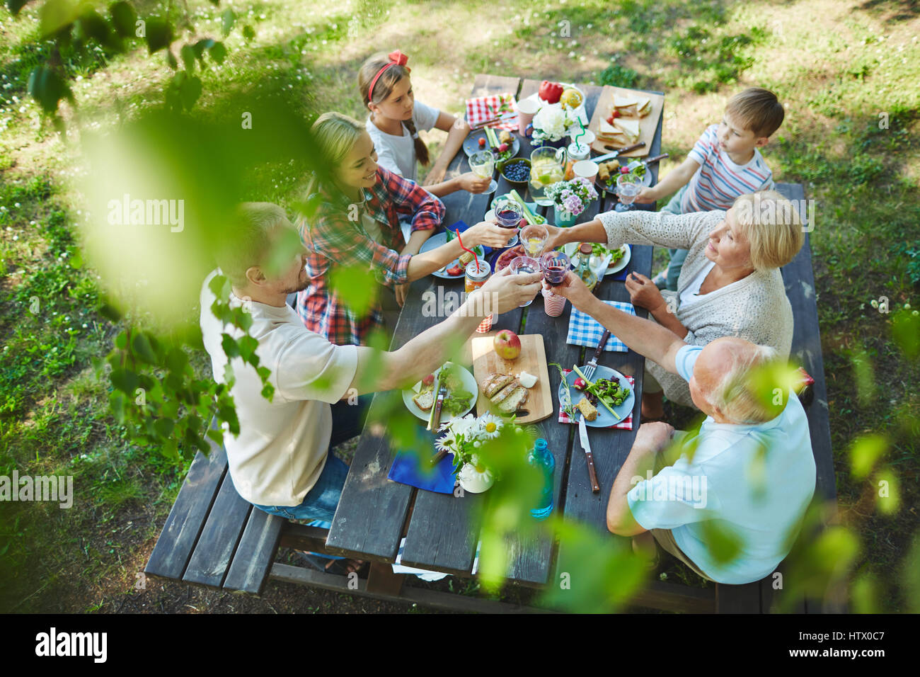 Young and senior couples cheering up with red wine by served table Stock Photo
