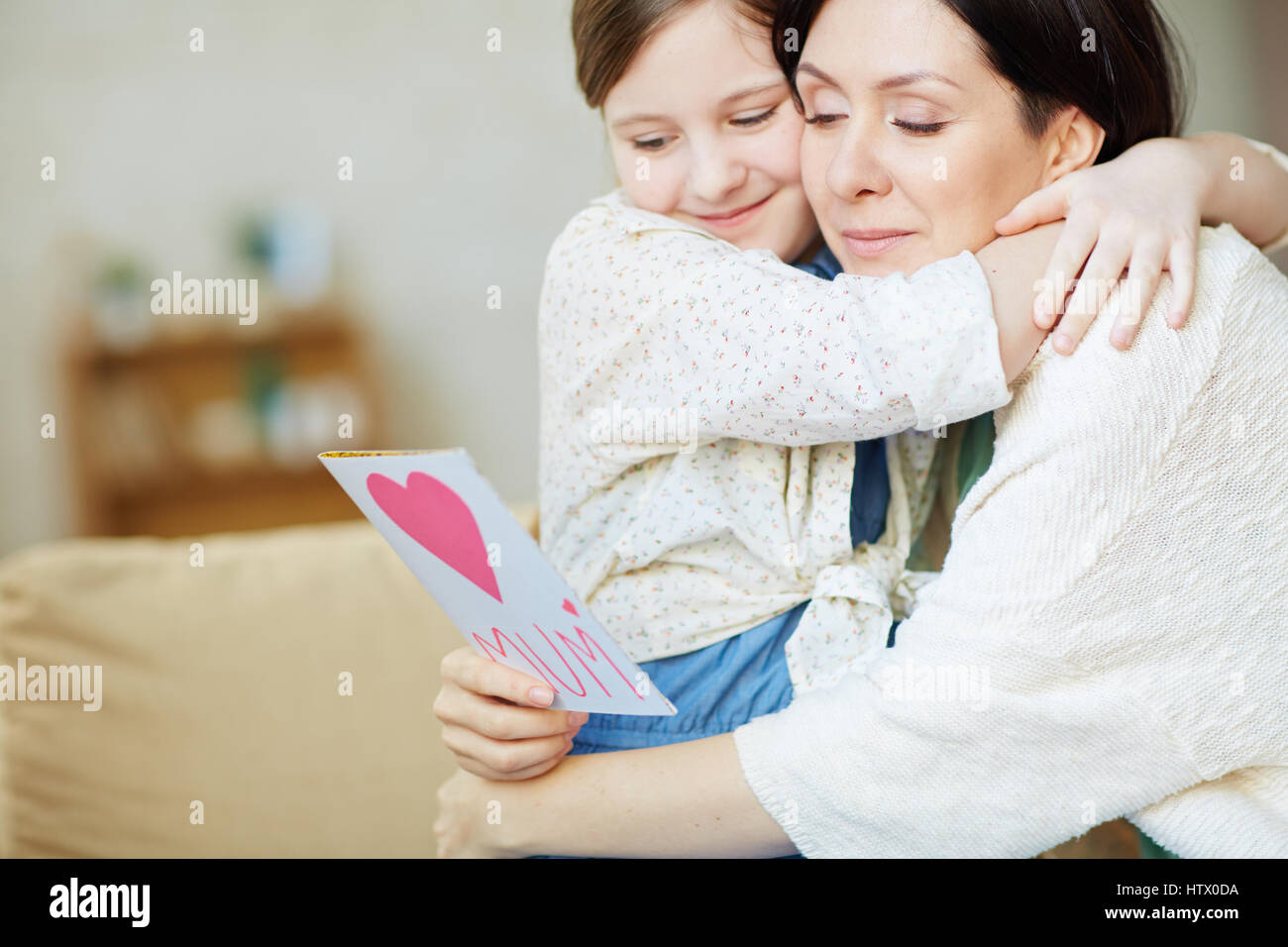 Girl and young woman in embrace reading greetings for mother day Stock Photo