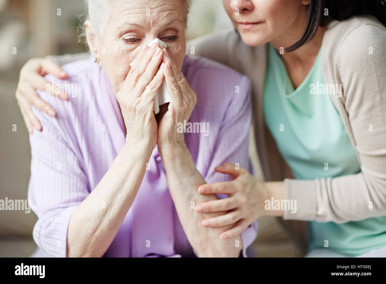 Elderly woman crying and young female embracing her Stock Photo