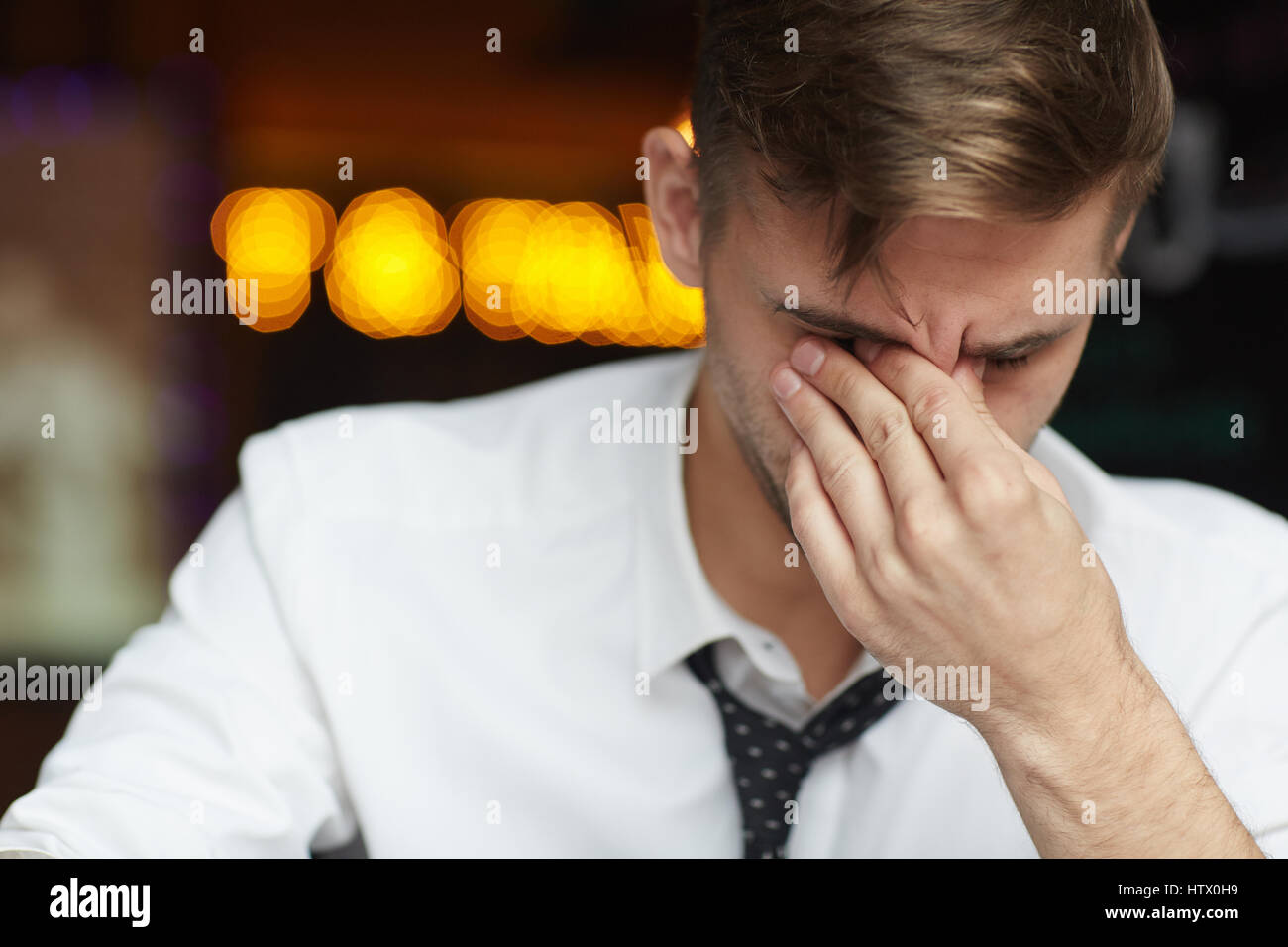 Portrait of tired young businessman wearing shirt and tie rubbing eyes