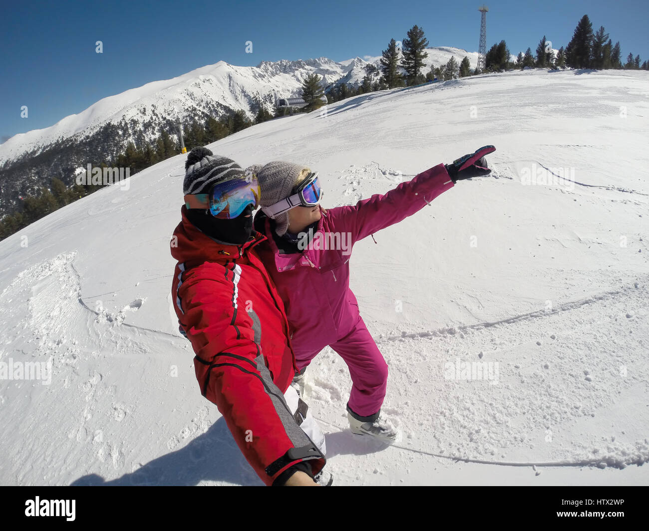 Skier couple on snowy mountainside show something in distance Stock Photo