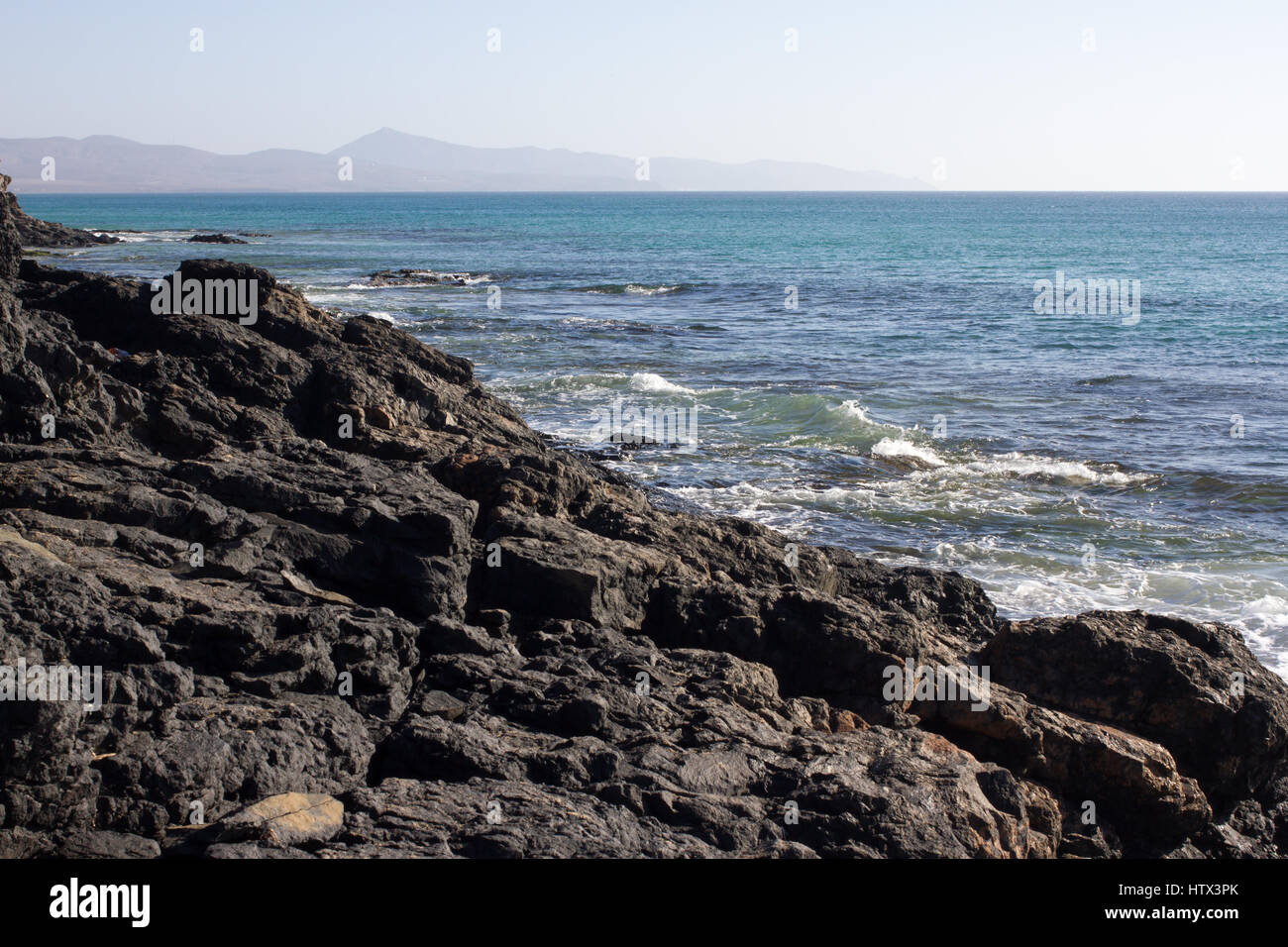 Black rocks of Costa Calma beach. Blue coastline. Playa Barca, Fuerteventura, Canary islands, Spain. Istmo de la pared view Stock Photo