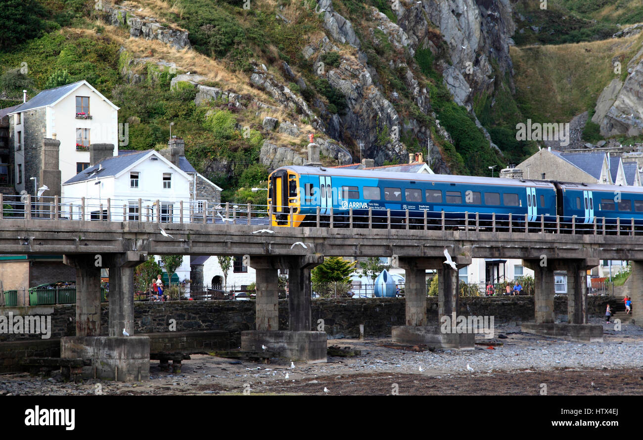 A passenger train crosses the harbour at Barmouth as approaches the station, Barmouth, Wales, Europe Stock Photo