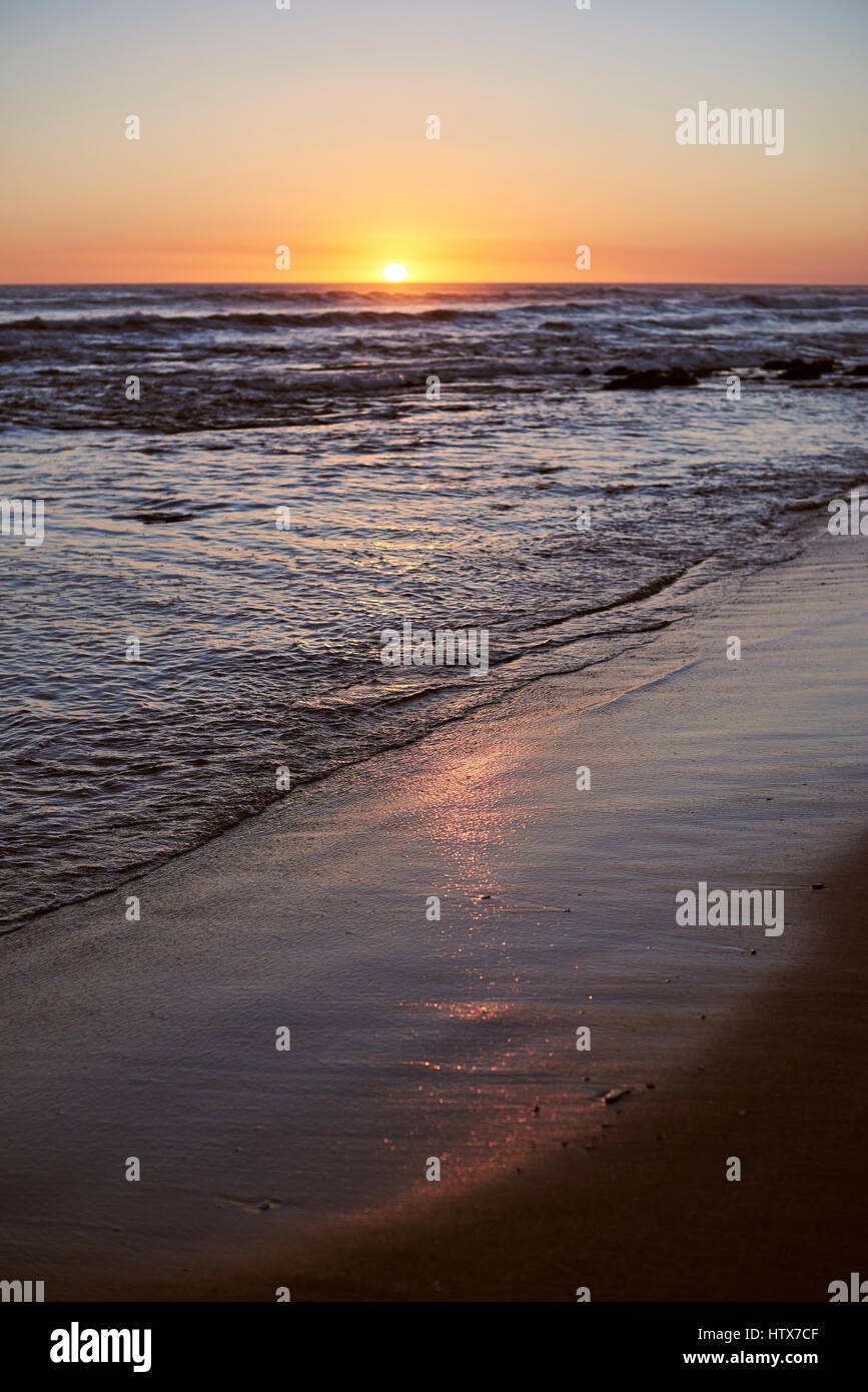 Sunrise reflection on beach sand vertical orientation. Pacific ocean coastline Stock Photo