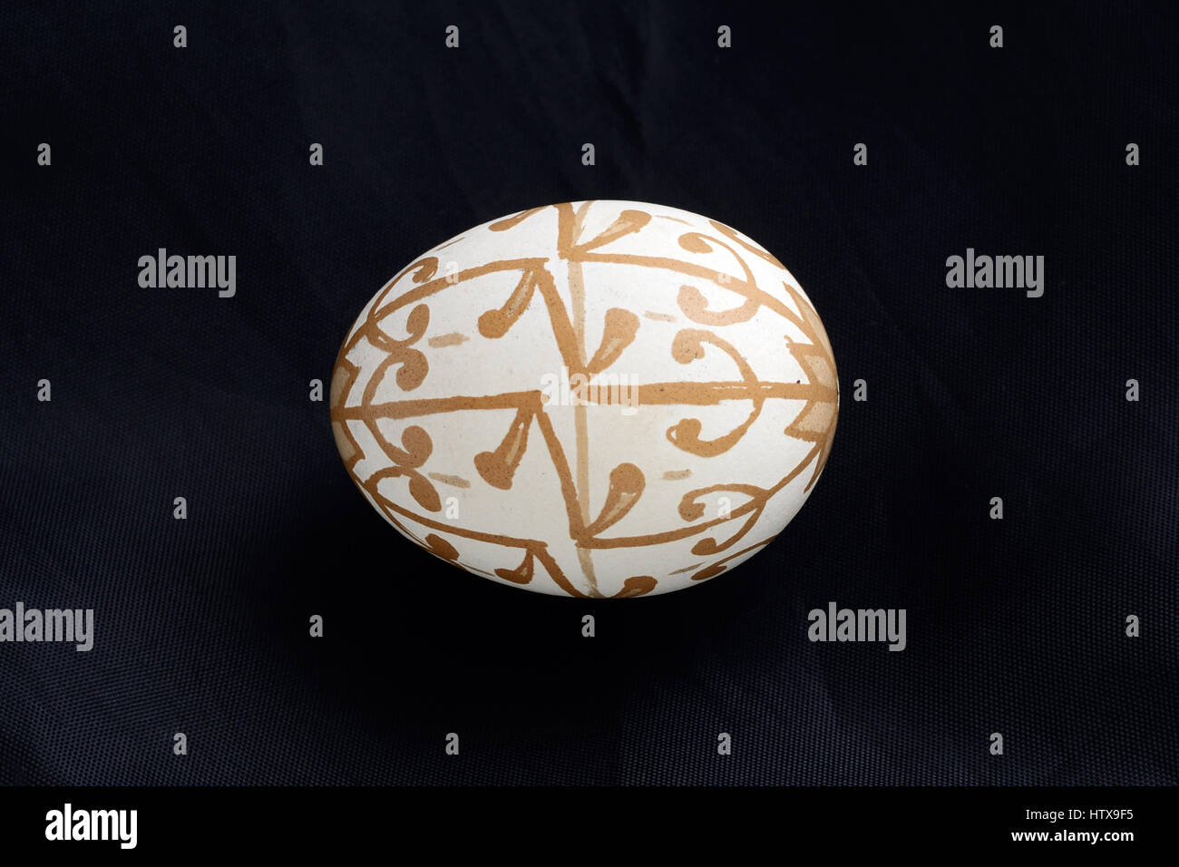 The Easter egg is decorated with a pattern using a wax-resist method and bleaching. Stock Photo