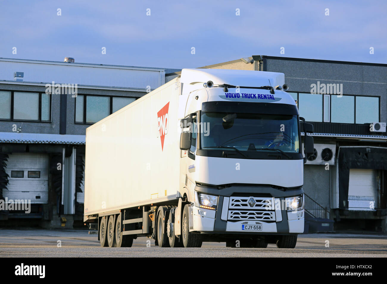 SALO, FINLAND - MARCH 12, 2017: White Renault Trucks T semi regfrigerated trailer exits warehouse yard in the evening to deliver a load, loading bays  Stock Photo